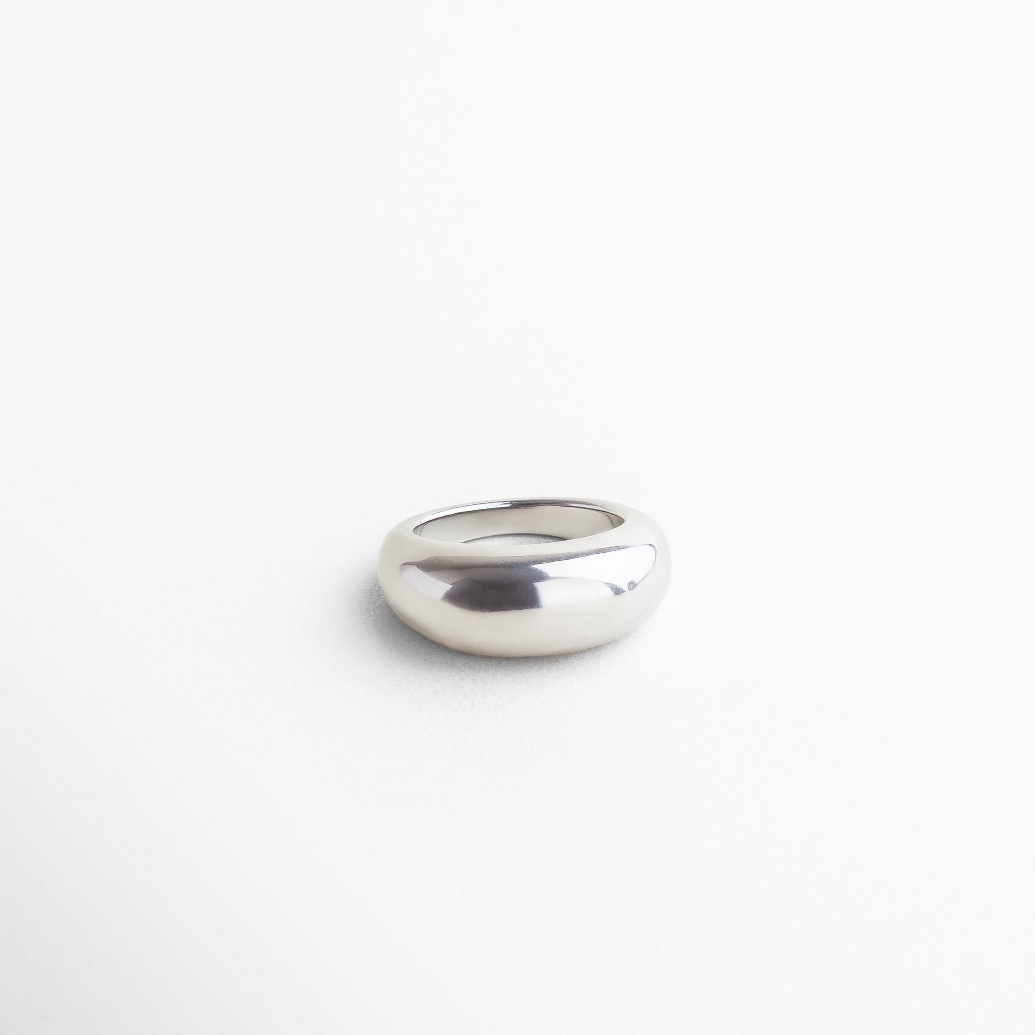 Vista superior del anillo Katerina en acabado plateado, mostrando su parte más alta de 7 mm y superficie lisa. Anillo plateado Katerina visto desde arriba, con diseño elegante en acero inoxidable brillante. Toma cenital del anillo statement Katerina, resaltando su volumen y acabado metálico pulido. Anillo Katerina plateado desde vista superior, destacando su estructura bold y líneas limpias. Perspectiva superior del anillo Katerina, con acabado en acero inoxidable y diseño llamativo.