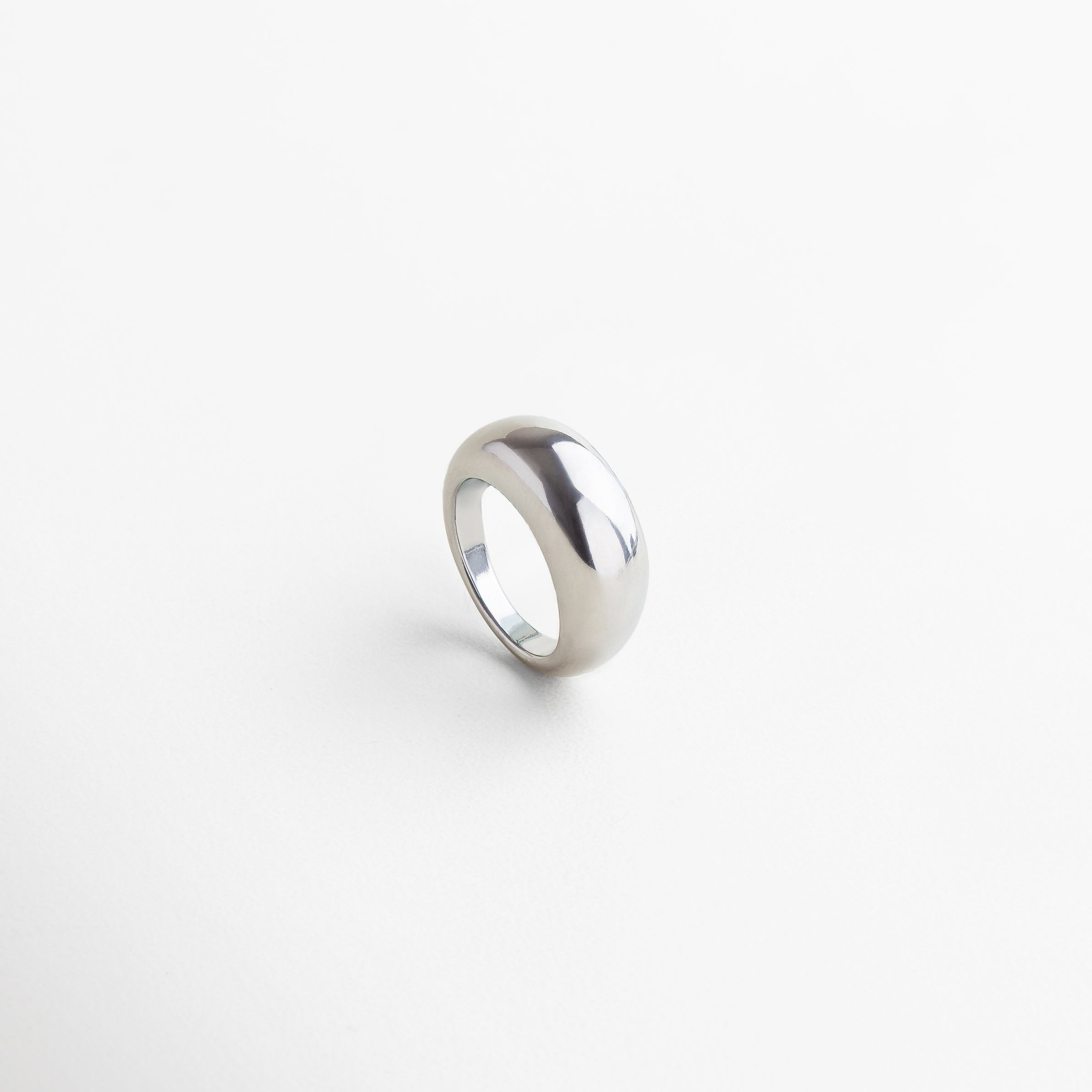 Anillo Katerina plateado visto desde el frente, con diseño voluminoso y elegante en acero inoxidable pulido. Vista frontal del anillo Katerina en acabado plateado, resaltando su estilo moderno y audaz. Anillo de acero inoxidable plateado desde el ángulo frontal, mostrando su grosor de 5 mm y silueta statement. Diseño frontal del anillo Katerina plateado, con acabado brillante y estructura contemporánea.
Primer plano del anillo plateado Katerina, vista frontal que destaca su forma sofisticada