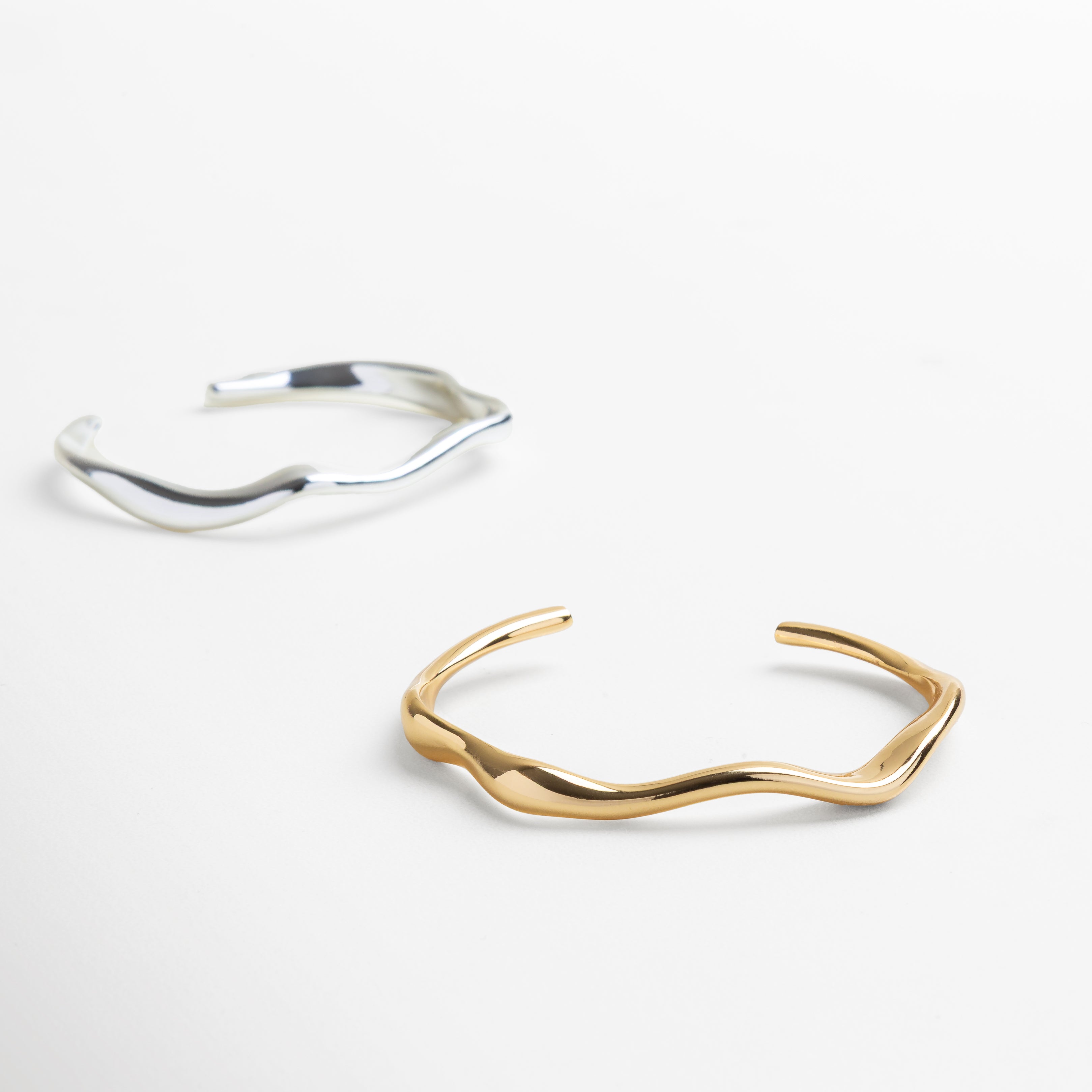 Brazalete mostrado sobre muñeca para referencia de tamaño, Proporciones del brazalete de 7.1 cm de ancho interior, Altura del brazalete de 5.4 cm visible en uso real, Tamaño adecuado para estilo minimalista y refinado, Joya en contexto con otras piezas de joyería