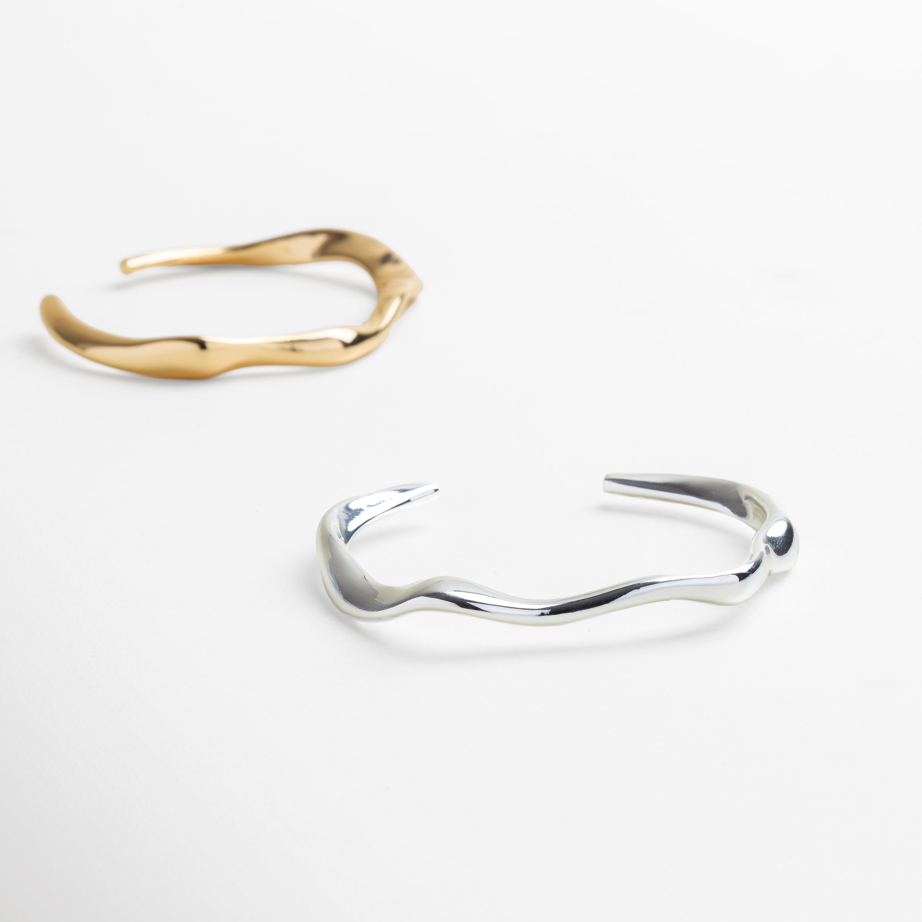 Brazalete mostrado sobre muñeca para referencia de tamaño, Proporciones del brazalete de 7.1 cm de ancho interior, Altura del brazalete de 5.4 cm visible en uso real, Tamaño adecuado para estilo minimalista y refinado, Joya en contexto con otras piezas de joyería