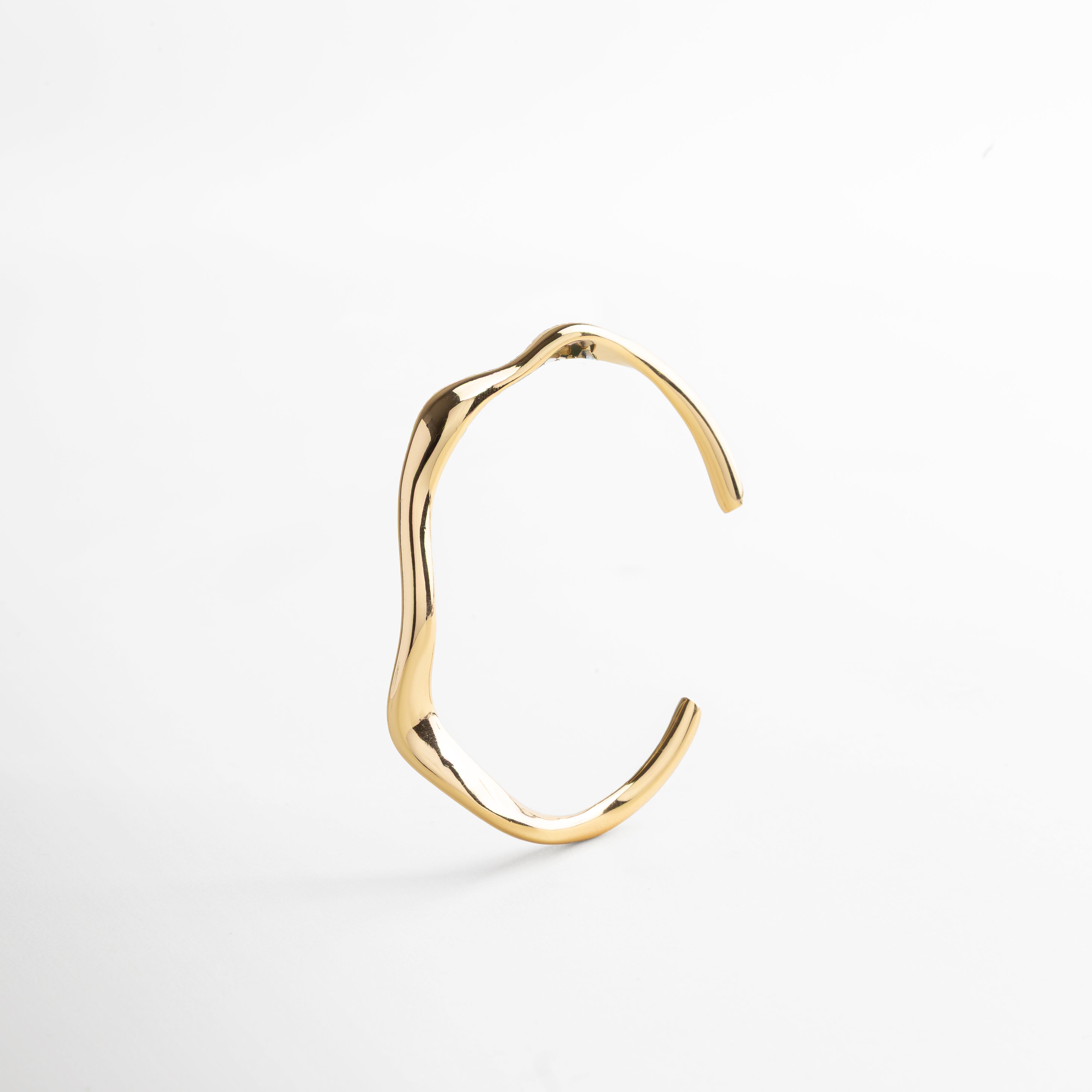 Primer plano del acabado pulido en oro 18K, Detalle de la superficie lisa y diseño orgánico del brazalete, Textura metálica fina con brillo cálido, Borde del brazalete con curvatura estilizada, Acabado de alta calidad en acero inoxidable resistente