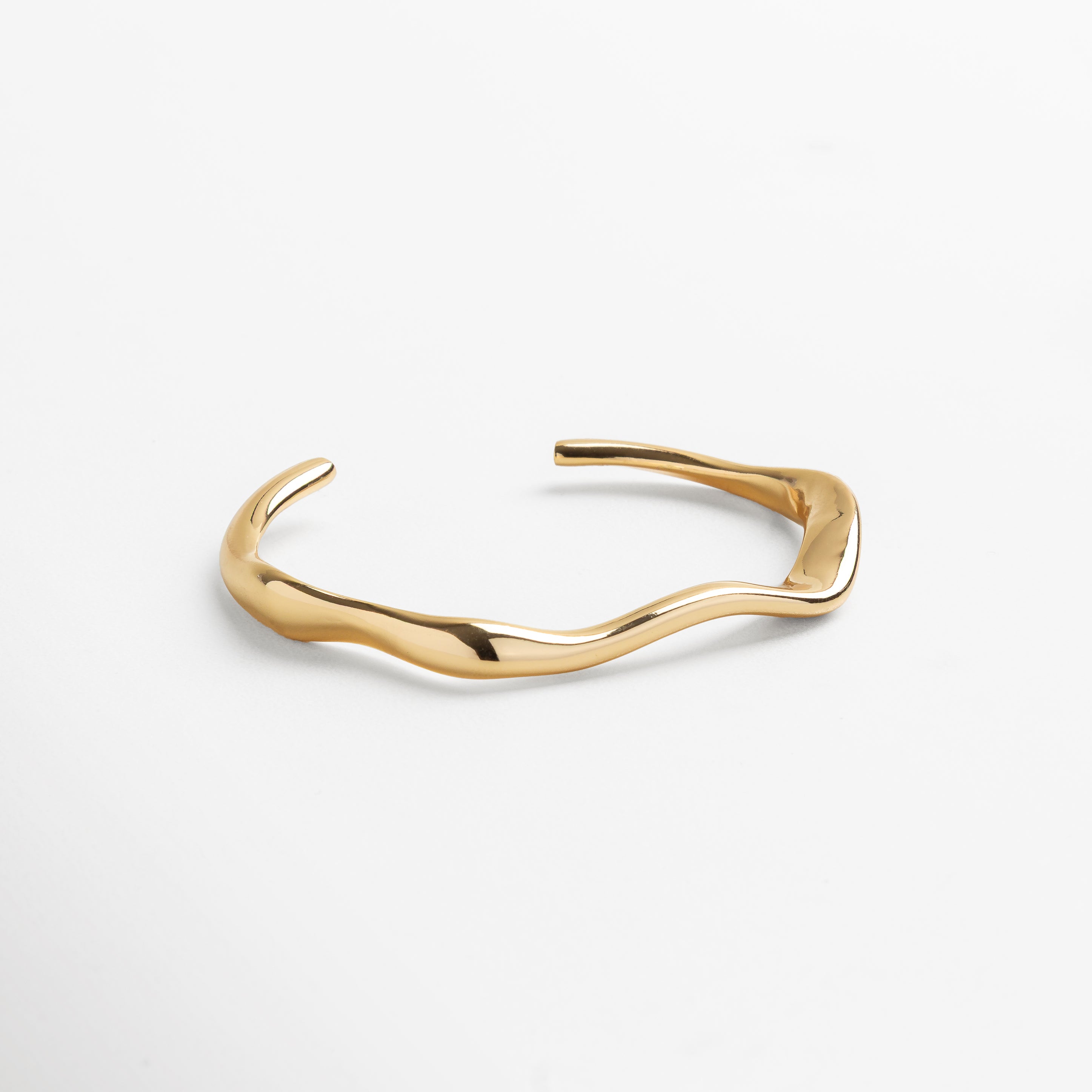 Brazalete rígido dorado con diseño orgánico contemporáneo, Pulsera minimalista en acero inoxidable con baño en oro 18K, Accesorio de joyería moderno y versátil para mujer, Brazalete elegante con acabado pulido en tono dorado, Joya rígida con estilo refinado y atemporal