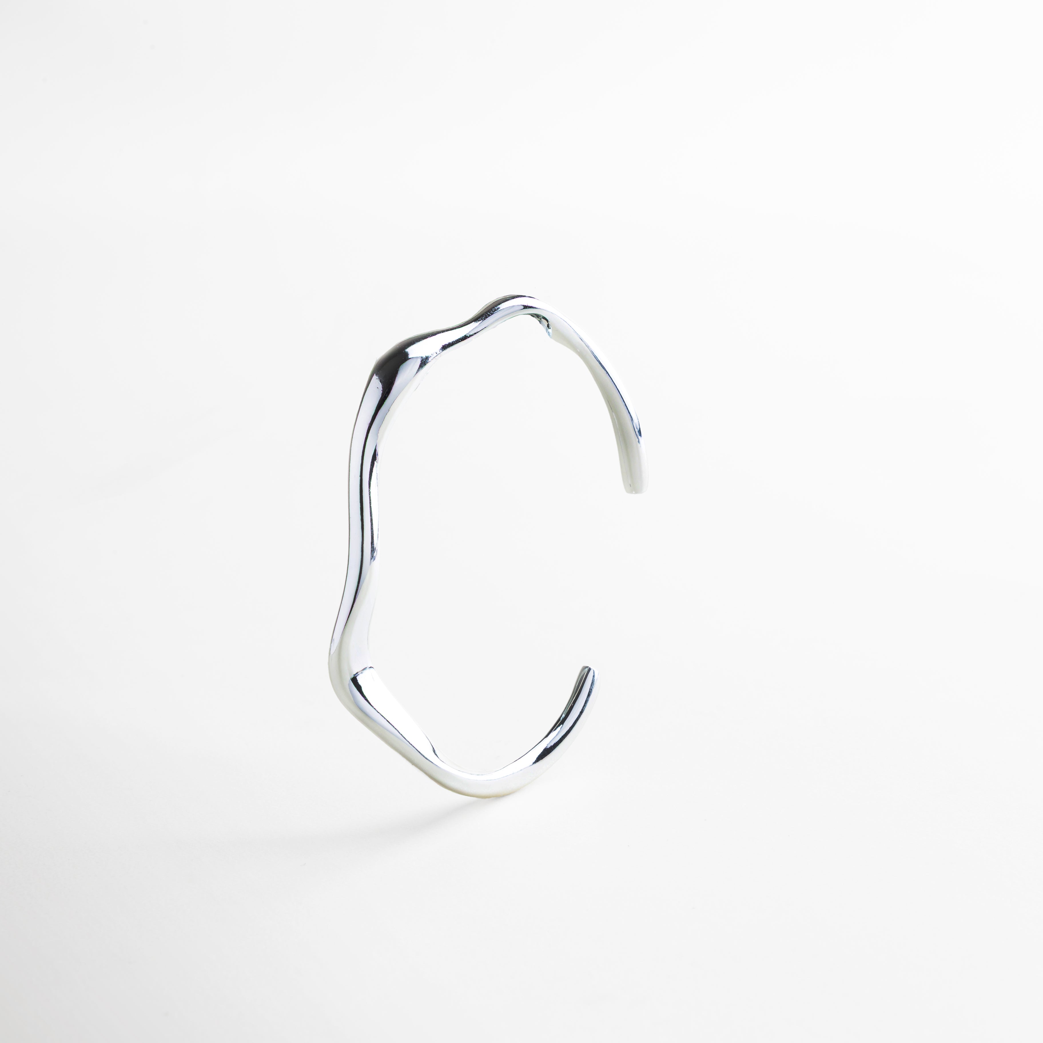 Primer plano del acabado pulido en oro blanco 18K, Detalle de la superficie lisa y diseño orgánico del brazalete, Textura metálica fina con brillo sutil, Borde del brazalete con curvatura estilizada, Acabado de alta calidad en acero inoxidable resistente