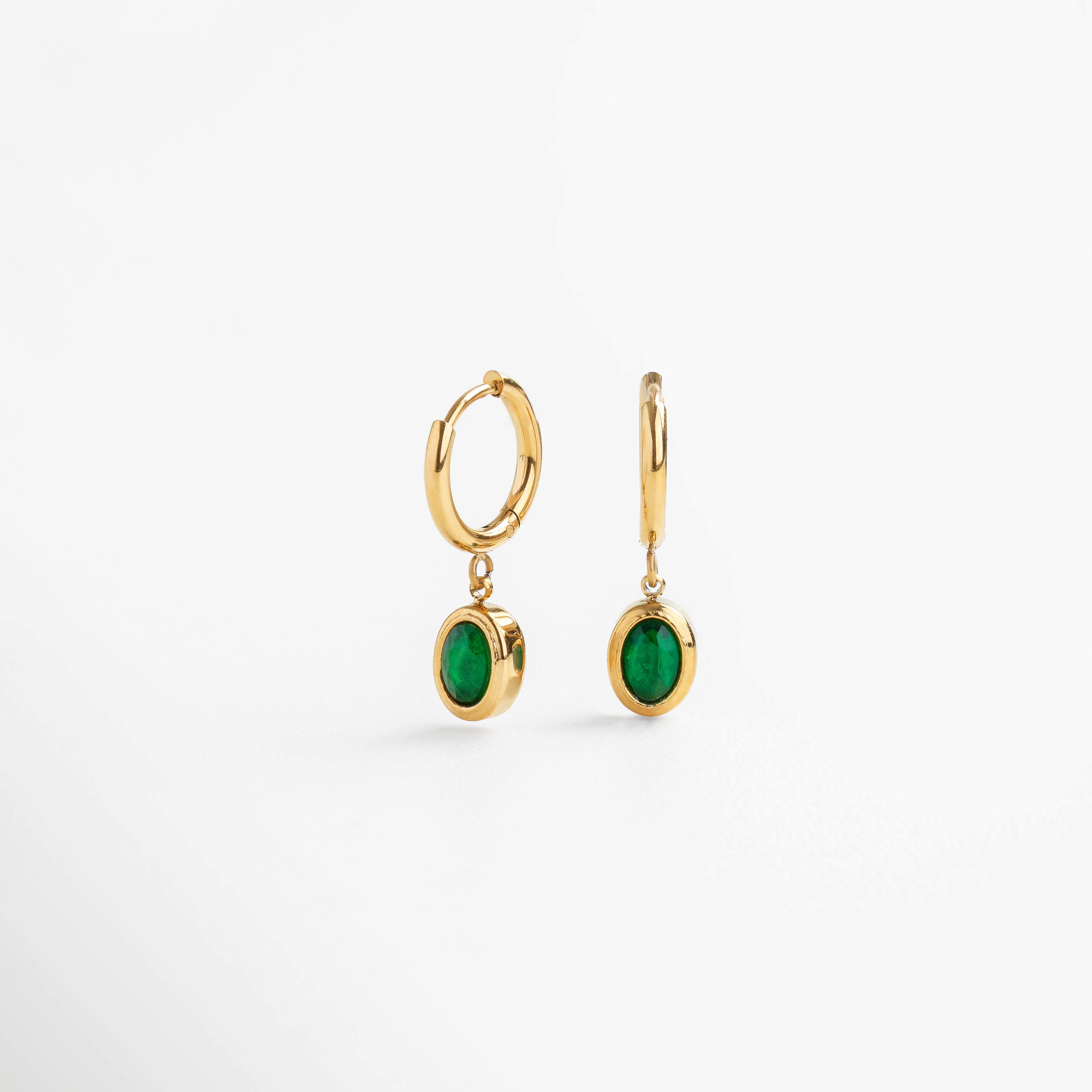 Detalle del dije verde en aretes con chapa de oro, Incrustación de zirconia verde en acabado pulido, Textura brillante en aretes con piedra colgante, Cierre y engaste en acero inoxidable dorado