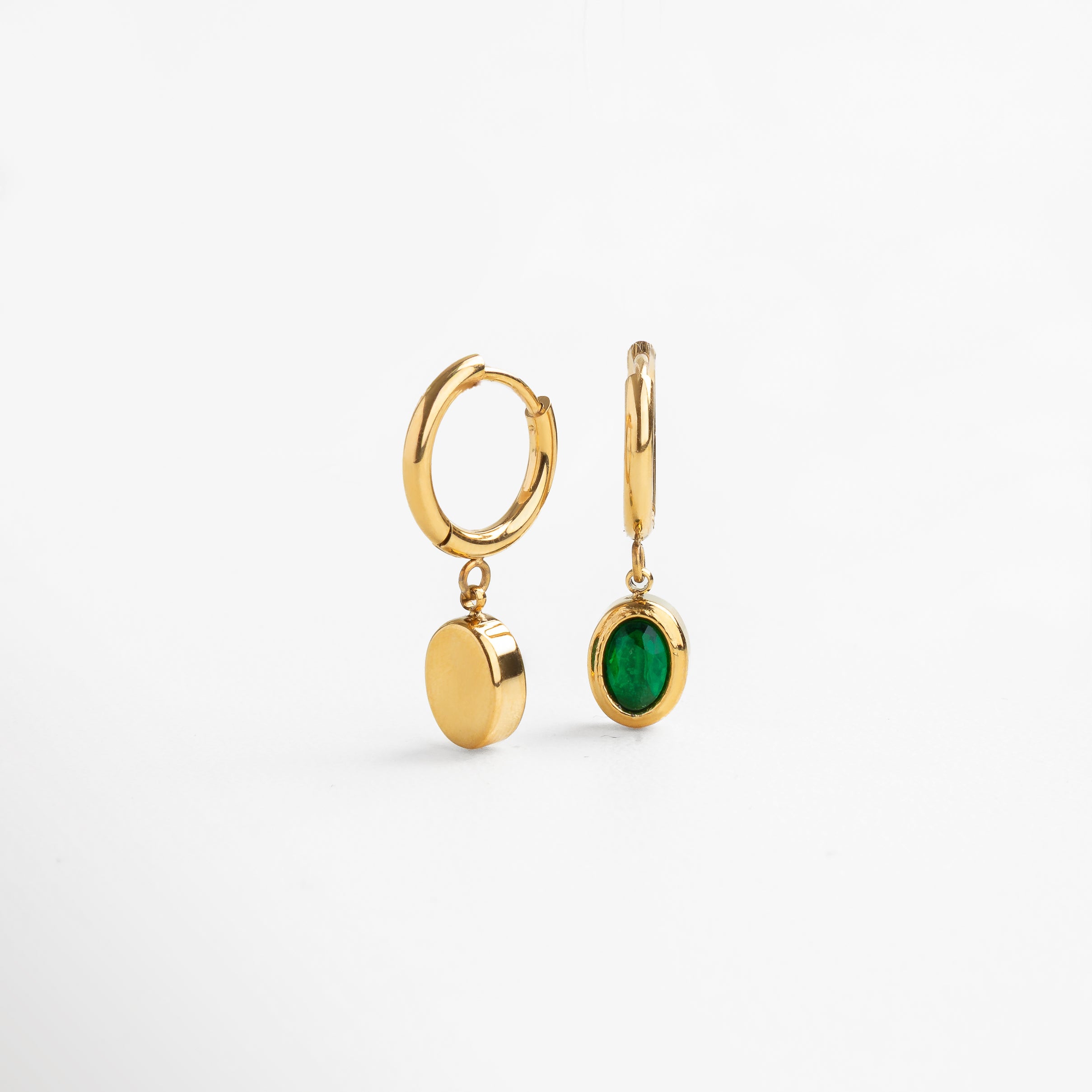 Perfil de aretes dorados con piedra verde colgante, Movimiento del dije verde desde vista en ángulo, Acabado dorado visto lateralmente con zirconia verde, Diseño clásico con giro moderno desde ángulo lateral