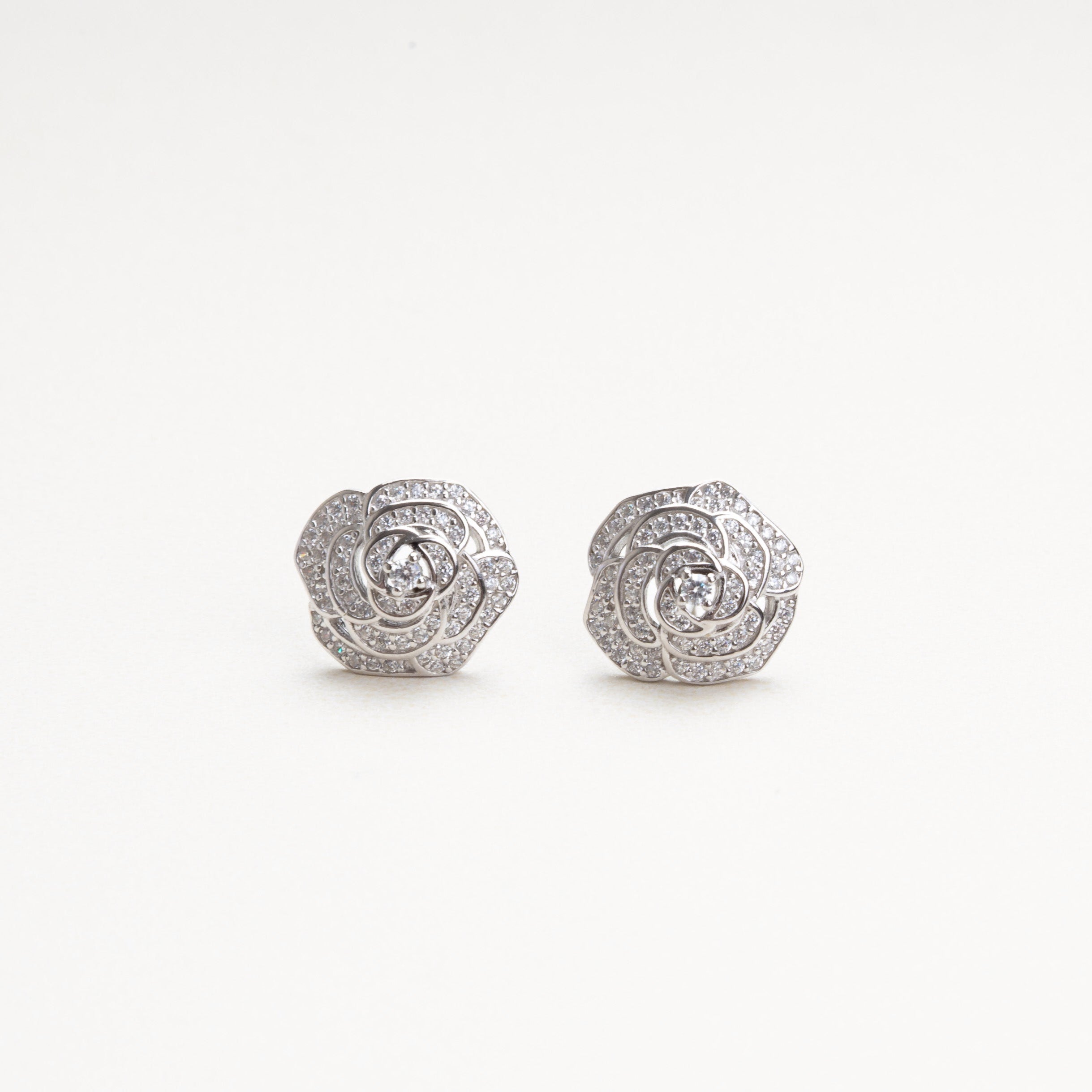 vista frontal de aretes pequeños y sofisticados en forma de flor cn incrustaciones de zirconias