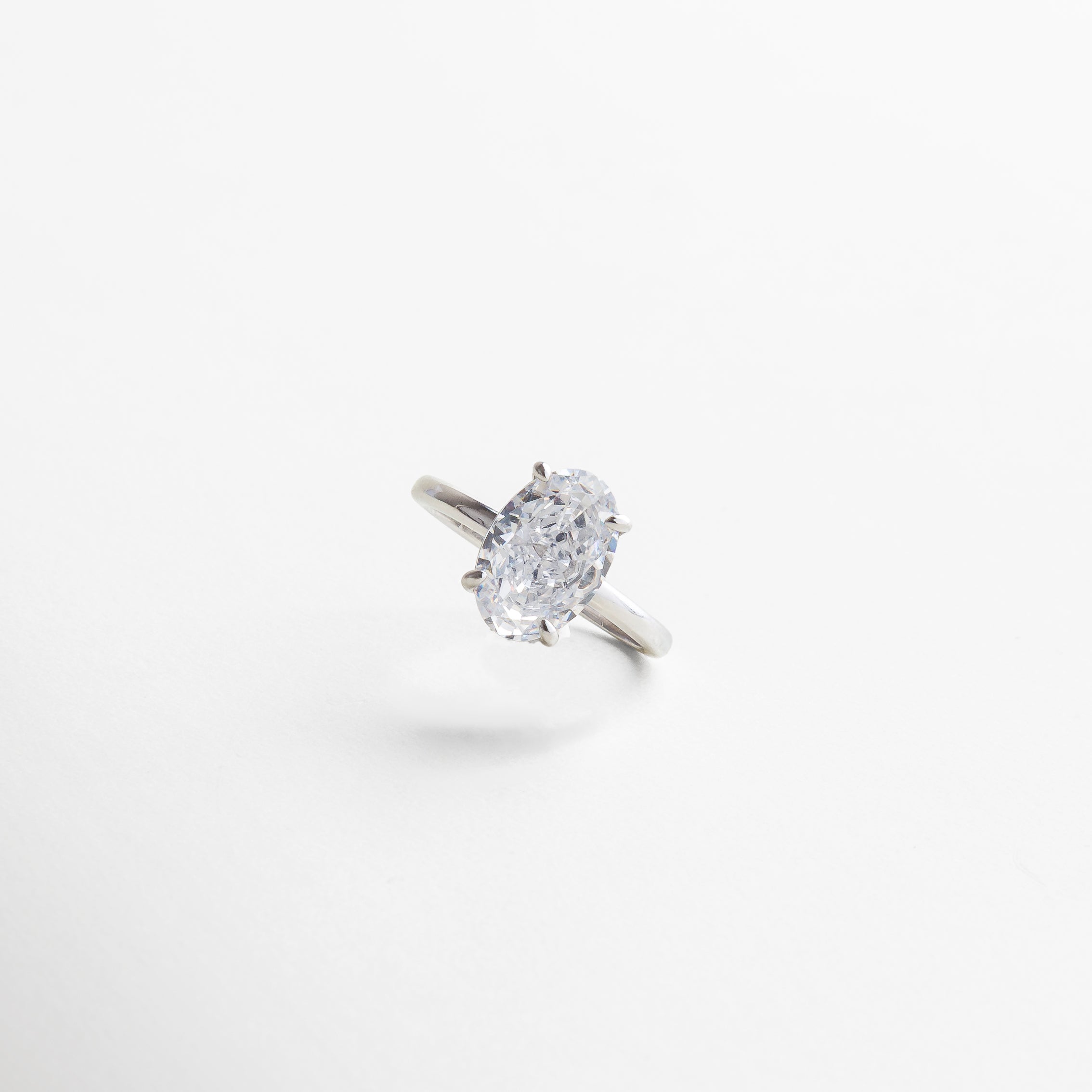vista macro de la zirconia cúbica, facetas precisas y luminosas, engaste meticuloso que potencia el destello, acabado uniforme en oro blanco 18K, contraste elegante entre metal y gema