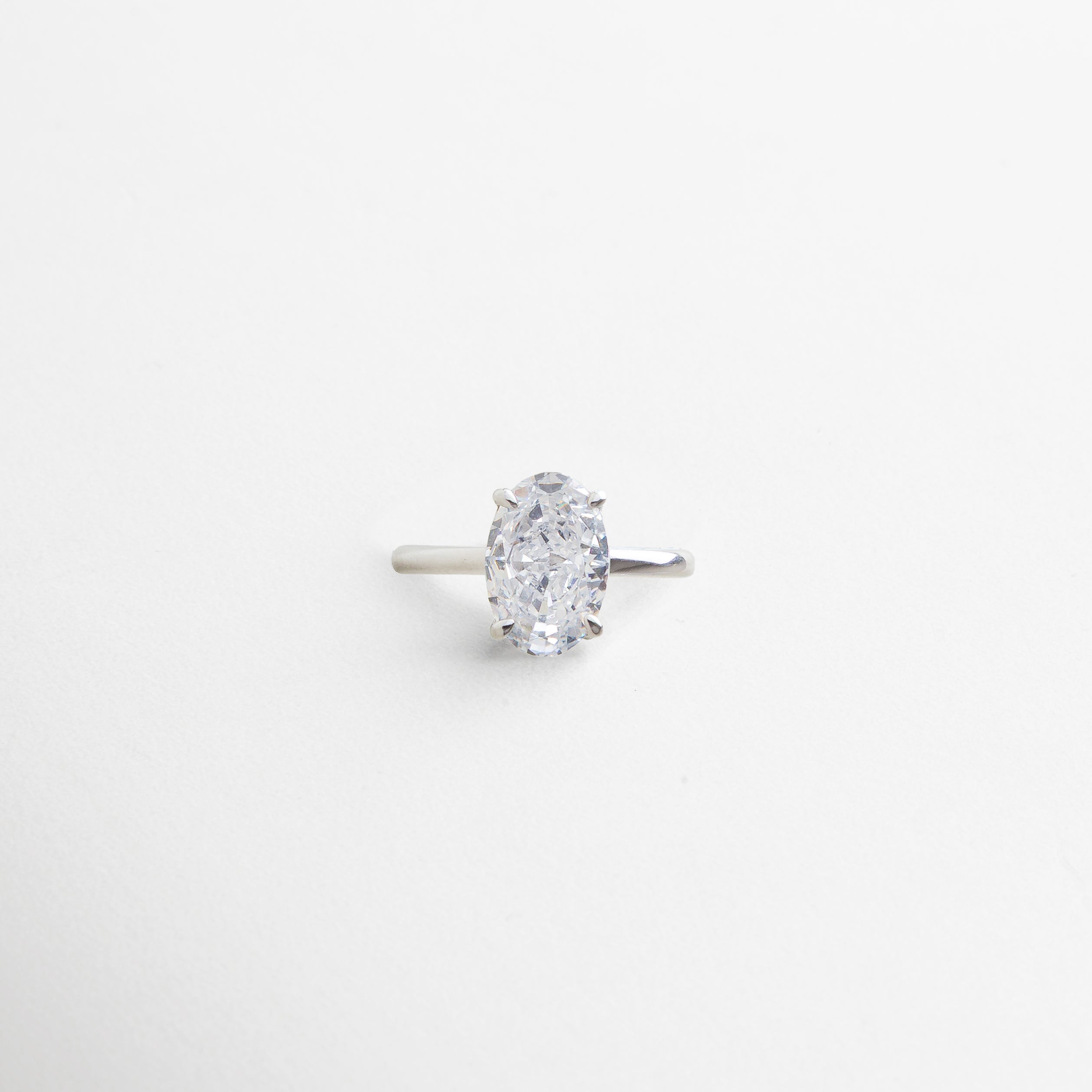 anillo plateado con piedra central ovalada de zirconia cúbica, acabado impecable en oro blanco 18K, diseño elegante y atemporal, pieza que simboliza momentos duraderos, joya versátil para cualquier ocasión