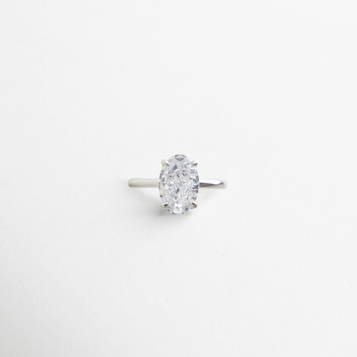 anillo plateado con piedra central ovalada de zirconia cúbica, acabado impecable en oro blanco 18K, diseño elegante y atemporal, pieza que simboliza momentos duraderos, joya versátil para cualquier ocasión