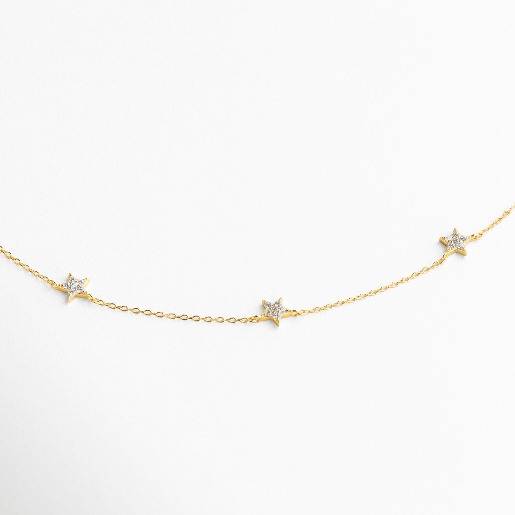 Detalle de charms en forma de estrella con incrustaciones de zirconias, acabado brillante que refleja la luz con sutileza, diseño elegante y versátil