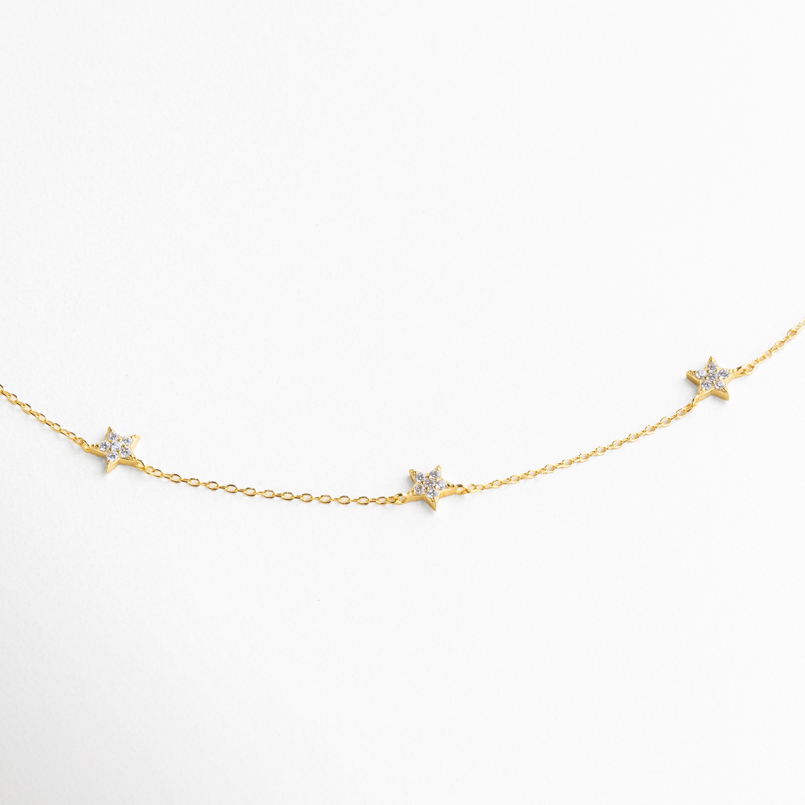 Detalle de charms en forma de estrella con incrustaciones de zirconias, acabado brillante que refleja la luz con sutileza, diseño elegante y versátil