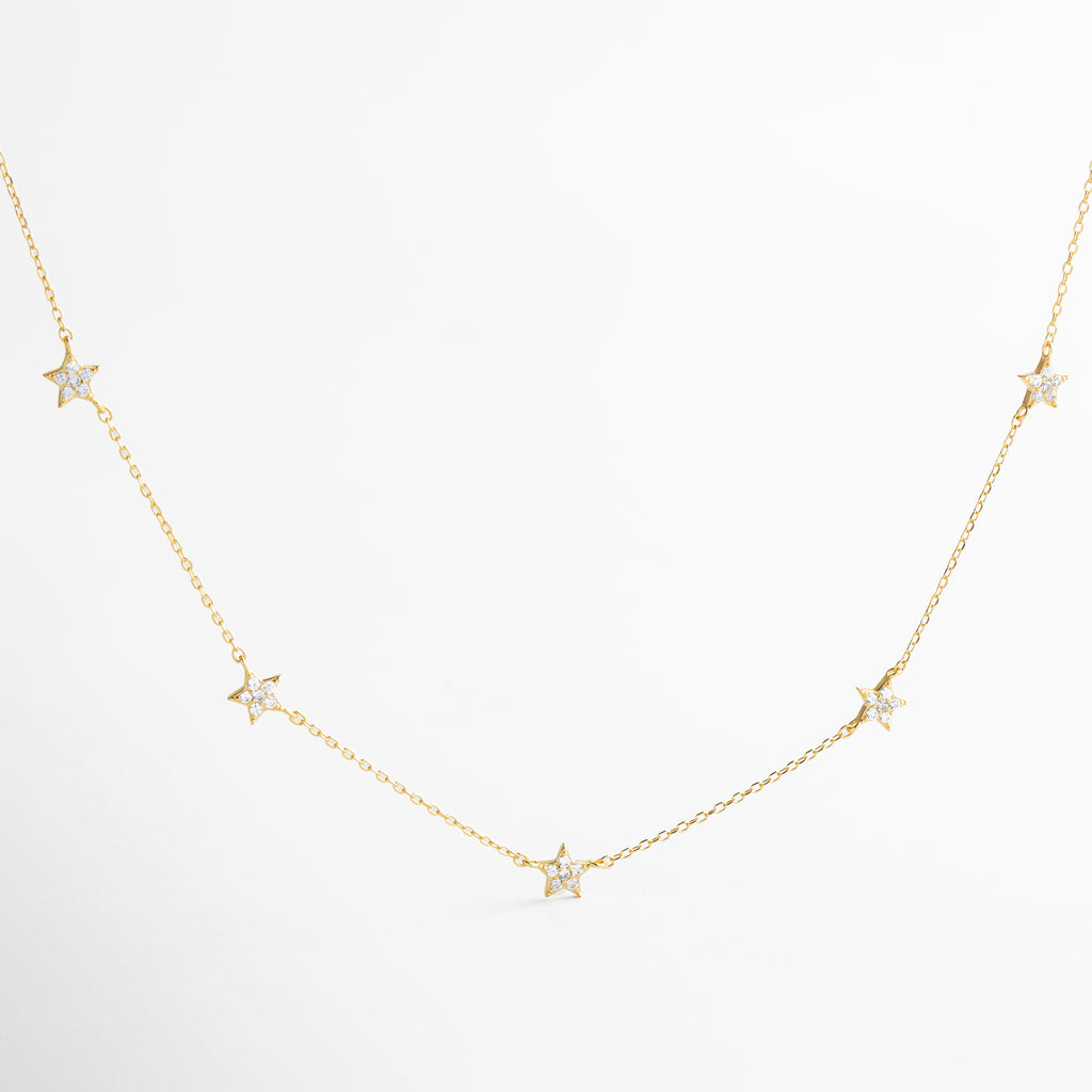 Collar dorado con charms de estrellas pavé, diseño delicado y luminoso, joyería inspirada en el brillo del cosmos, accesorio femenino ideal para looks románticos y modernos