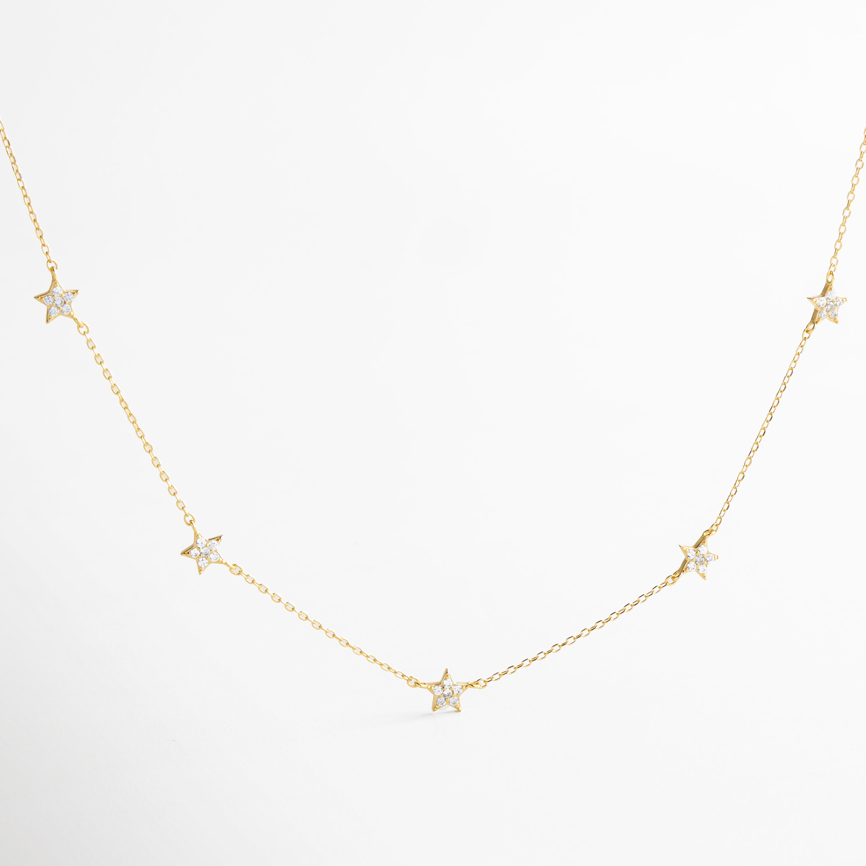 Collar dorado con charms de estrellas pavé, diseño delicado y luminoso, joyería inspirada en el brillo del cosmos, accesorio femenino ideal para looks románticos y modernos