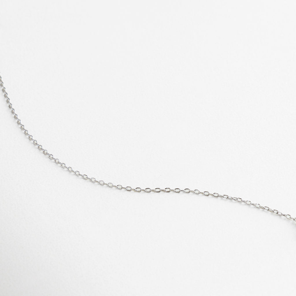Charm en forma de estrella con zirconias incrustadas, Acabado brillante y pulido en oro blanco, Detalle fino del engaste pavé, Zirconias que reflejan la luz con sutil elegancia, Textura suave y lustrosa de la cadena