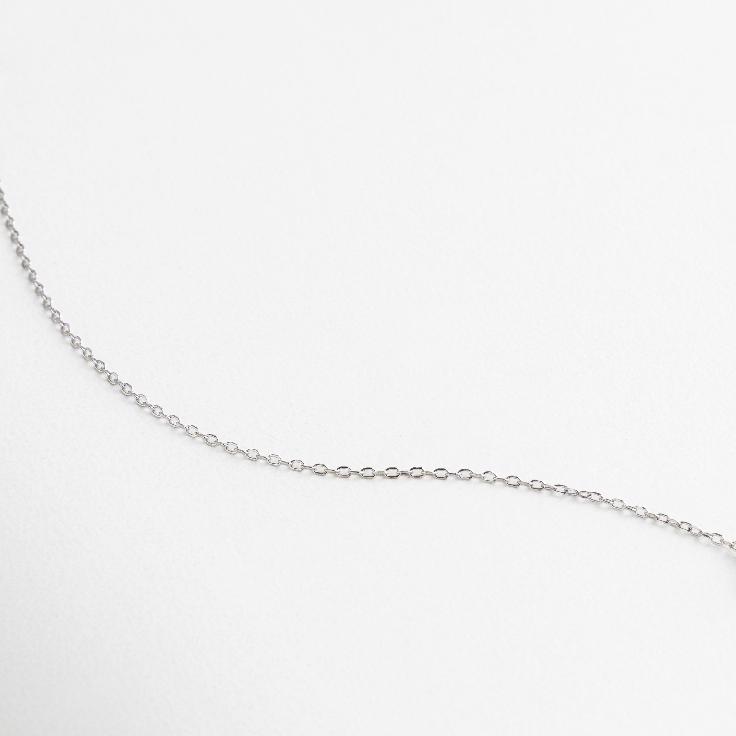 Charm en forma de estrella con zirconias incrustadas, Acabado brillante y pulido en oro blanco, Detalle fino del engaste pavé, Zirconias que reflejan la luz con sutil elegancia, Textura suave y lustrosa de la cadena