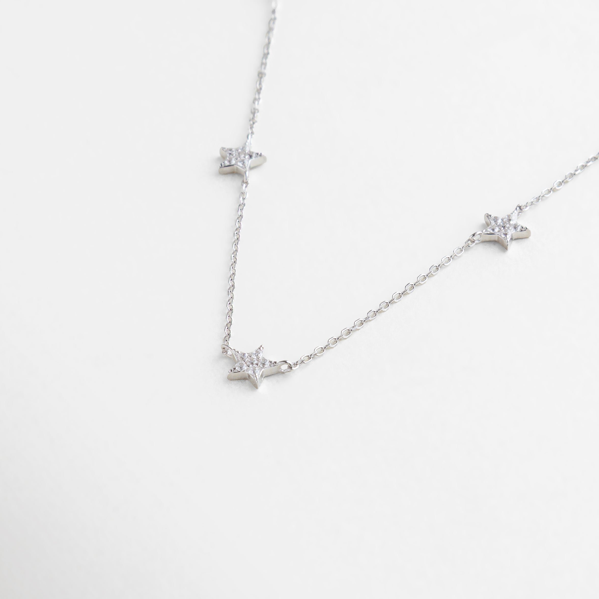 charms de estrellas pavé con zirconias brillantes, textura de la cadena delgada y dijes estrellados, vista cercana del engarce de zirconias en forma de estrella, detalle brillante de estrellas miniatura con acabado pulido, incrustaciones de zirconias sobre estrellas chapadas en plata