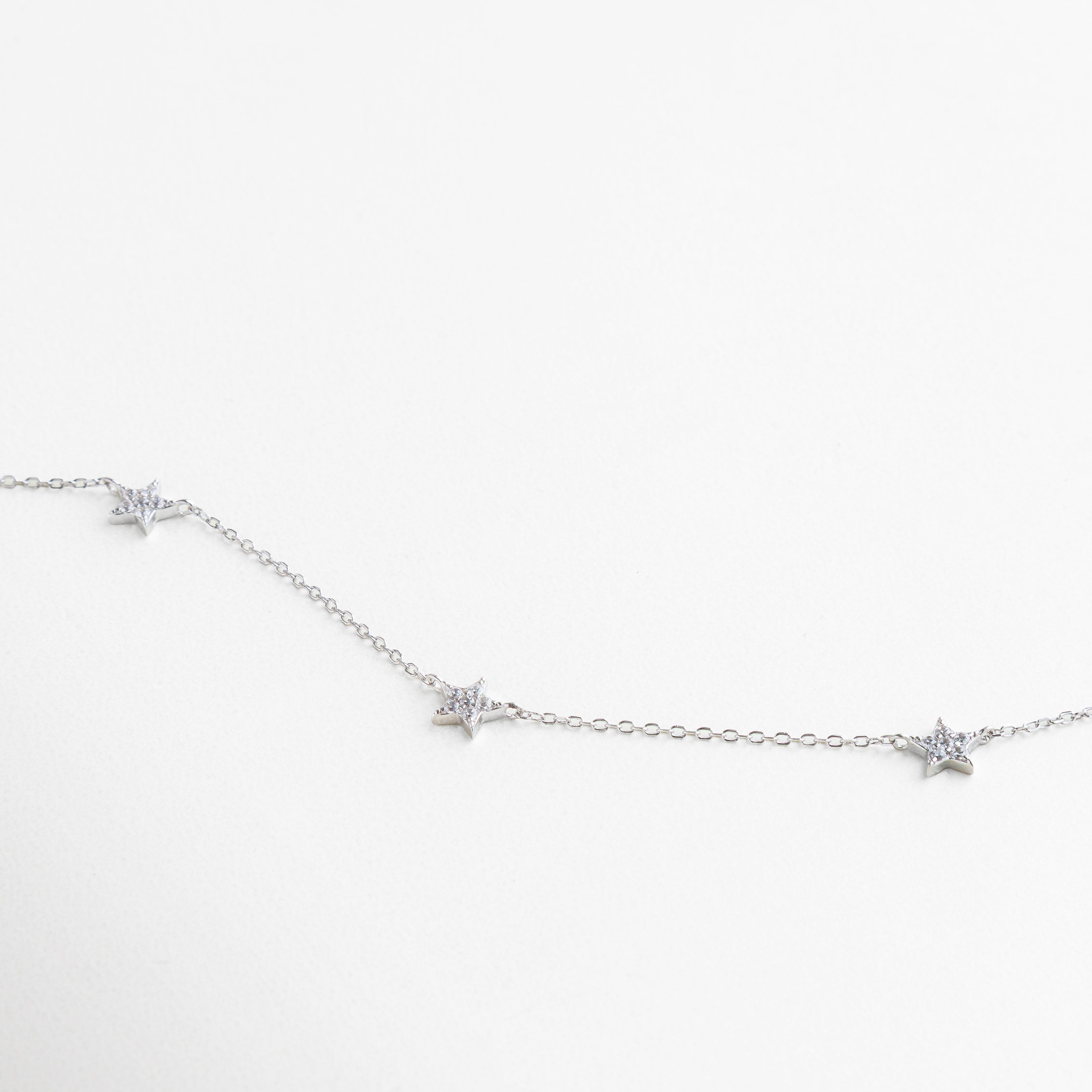 dimensión real del collar con charms de estrellas, proporción del collar brillante sobre el pecho, comparación del tamaño de los dijes con el largo de la cadena, vista de escala del collar plateado con zirconias, collar estrellado mostrado en relación a otros accesorios