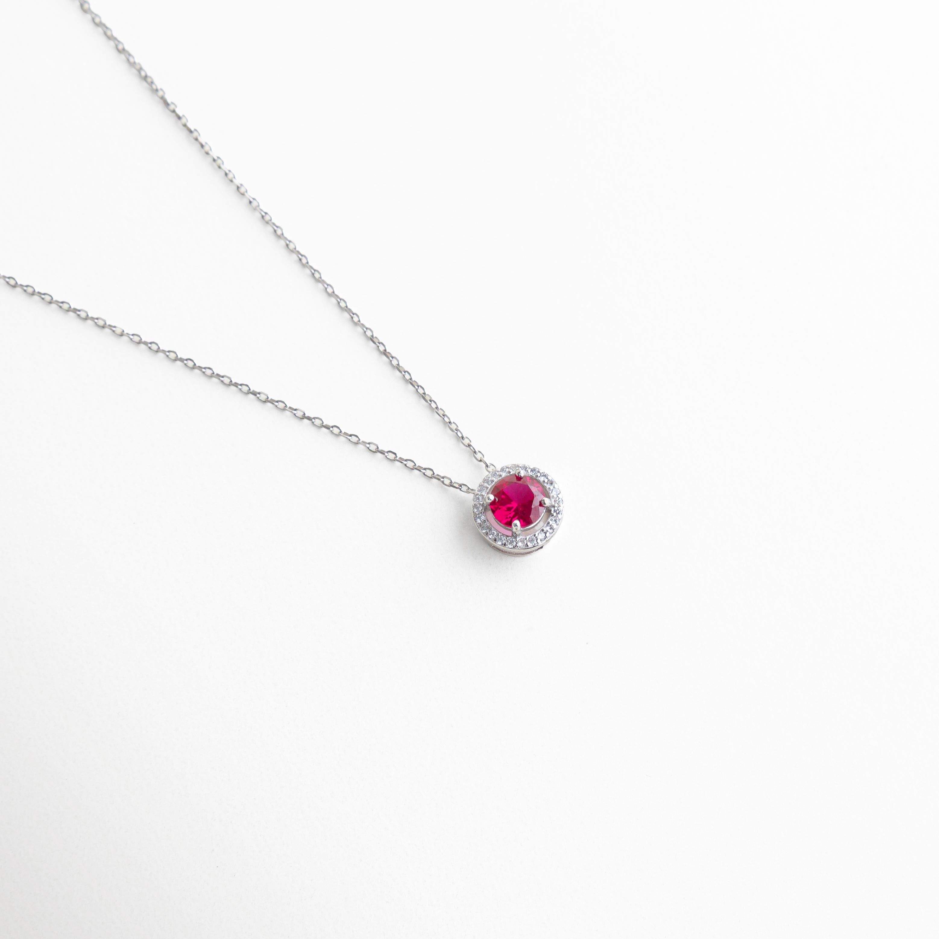 collar plateado con zirconia roja central y halo de zirconias, collar delicado con dije redondo rojo brillante, collar minimalista con piedra roja rodeada de zirconias, collar femenino con colgante rojo elegante, collar plateado con piedra roja circular