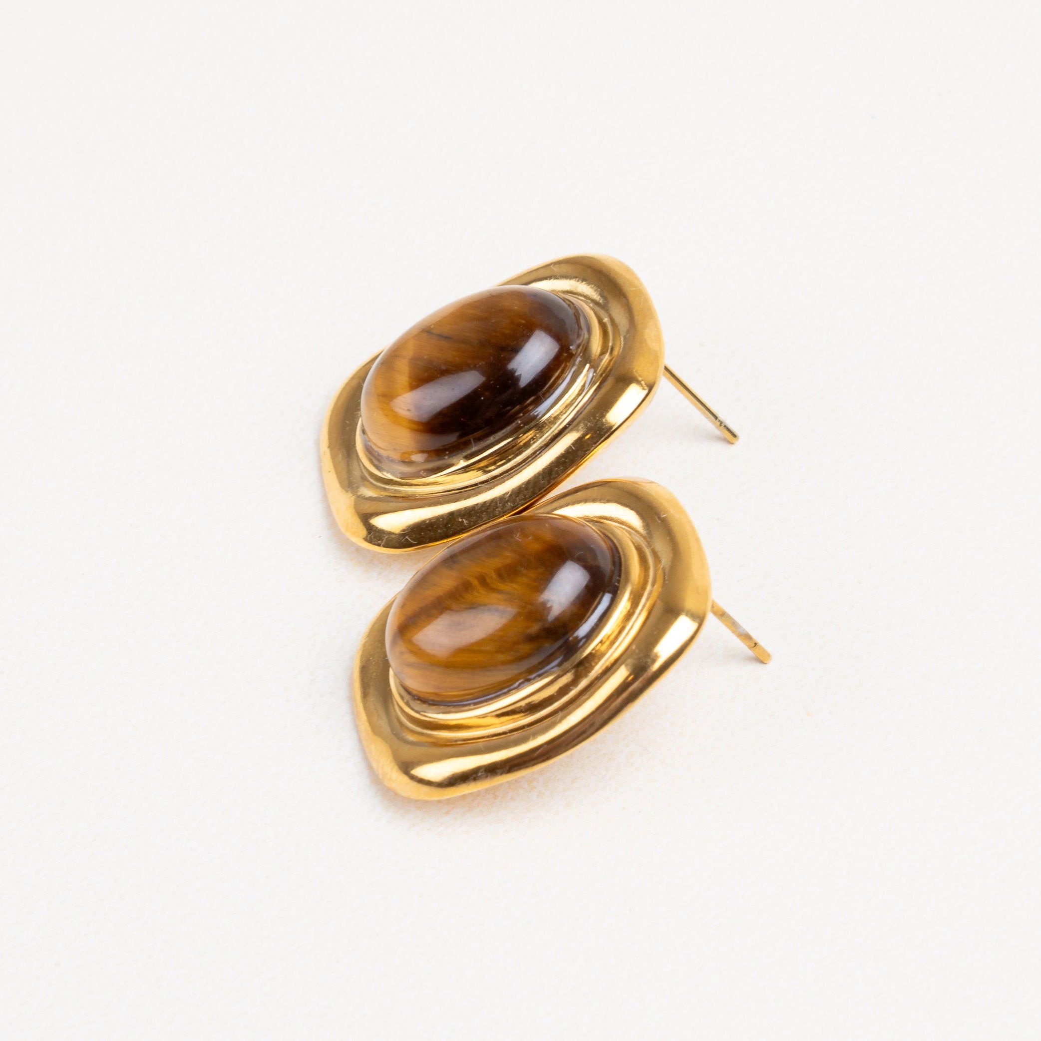 Detalle cercano de la piedra ojo de tigre en aretes cuadrados, con borde doradobrillante.