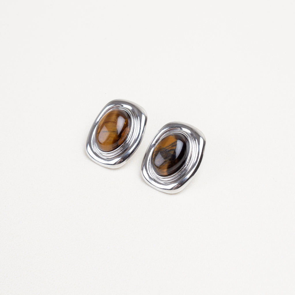 Detalle cercano de la piedra ojo de tigre en aretes cuadrados, con borde dorado o plateado brillante