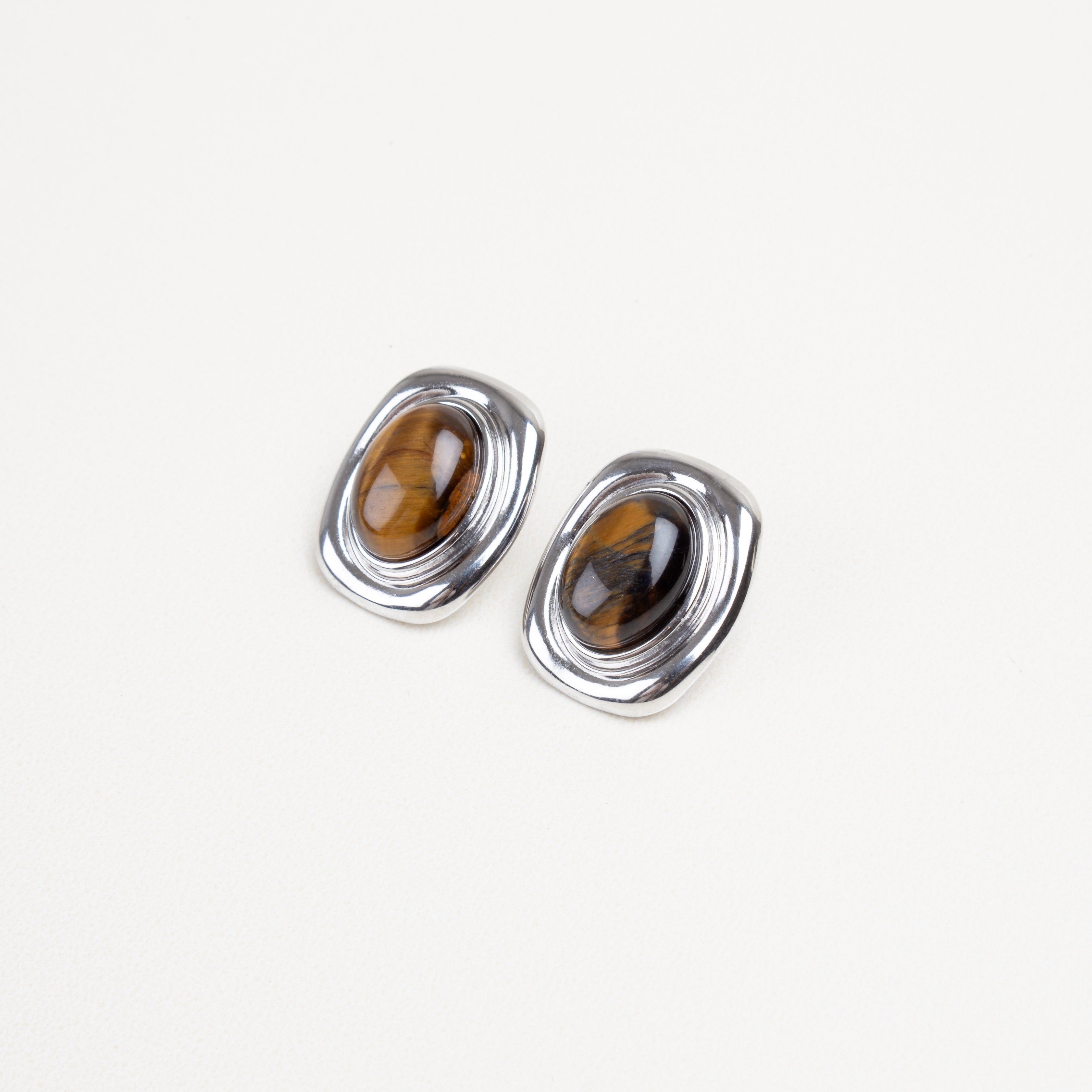 Detalle cercano de la piedra ojo de tigre en aretes cuadrados, con borde dorado o plateado brillante