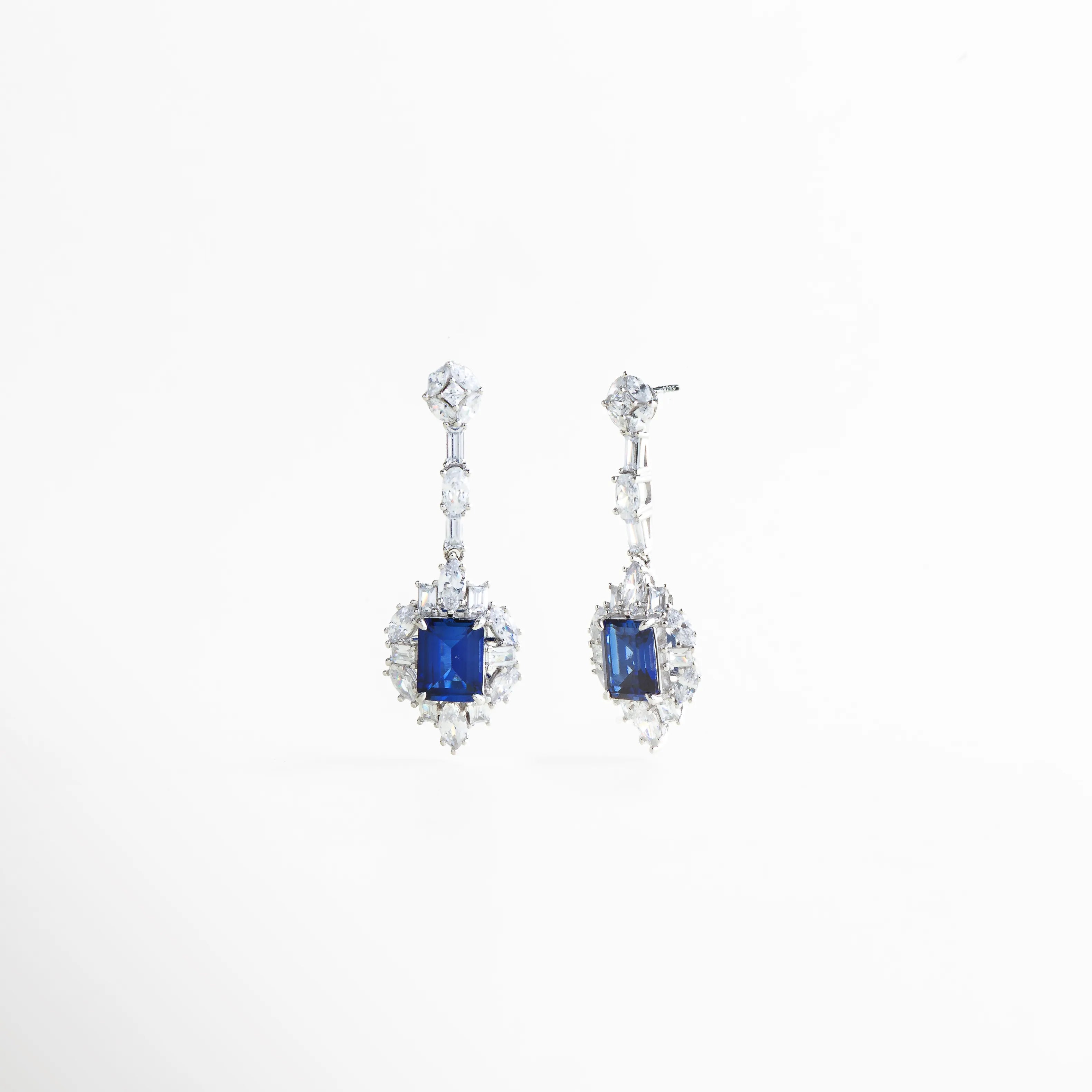Vista de perfil de los aretes Cordelia Azules mostrando el poste de plata y el grosor de la joya, Pendientes largos con caída estructurada y piedras de laboratorio, vista lateral técnica,Estructura de los aretes de gala Cordelia, resaltando el diseño fluido y la calidad del metal, Vista lateral de joyería fina en plata 925 con piedras azules y blancas de corte brillante, Detalle del sistema de sujeción y balance de los aretes largos Cordelia Azules.