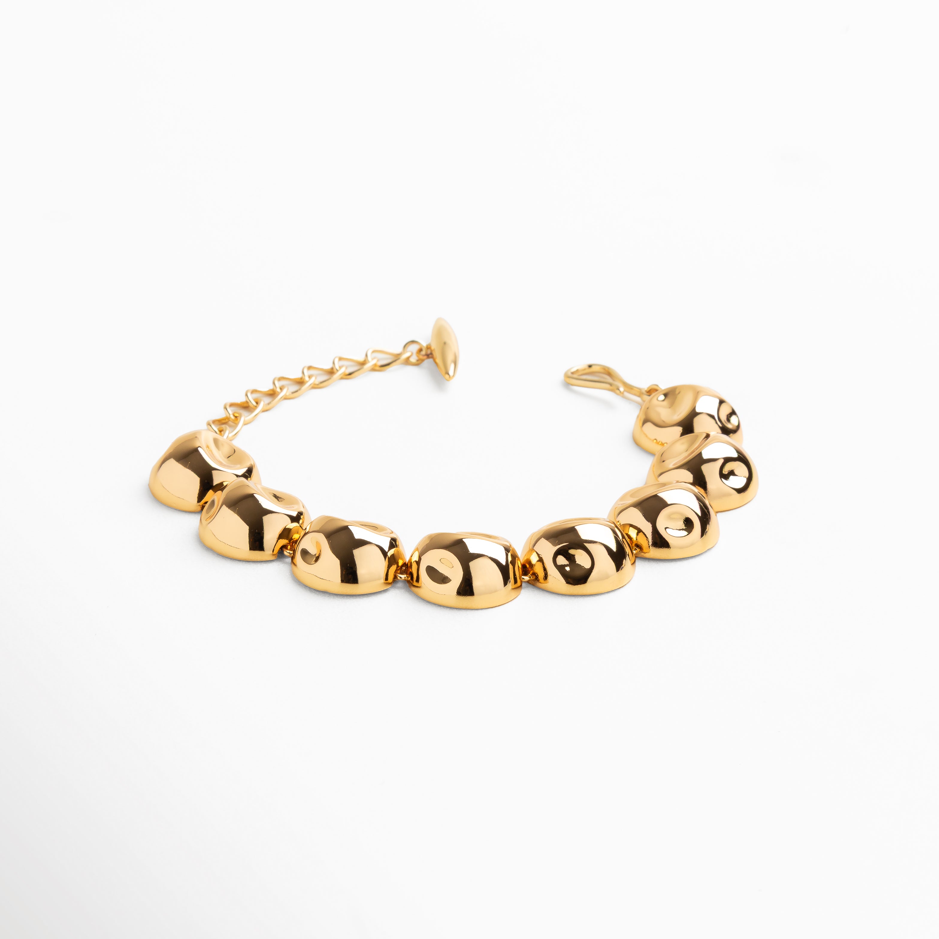 Primer plano de esferas doradas pulidas con reflejo brillante, Detalle de acabado espejo en cuentas metálicas doradas, Conexión uniforme entre bolitas en pulsera dorada, Superficie lisa y pulida de cada esfera, Textura brillante y continua en pulsera de cuentas doradas
