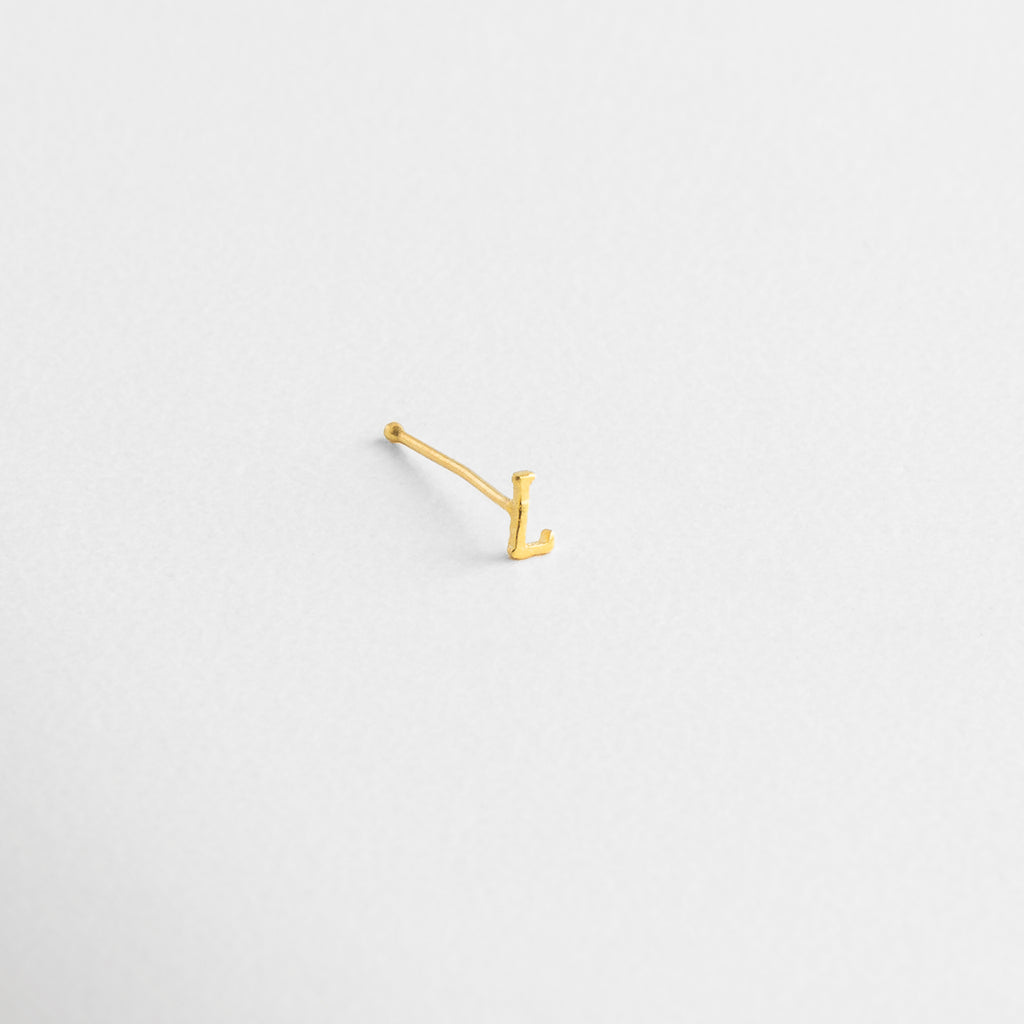 Letra dorada sobre fondo claro, Detalle de la curva o línea de la letra, Ángulo que muestra volumen del diseño, Relieve suave en Oro 18K, Perfil metálico perfectamente contorneado