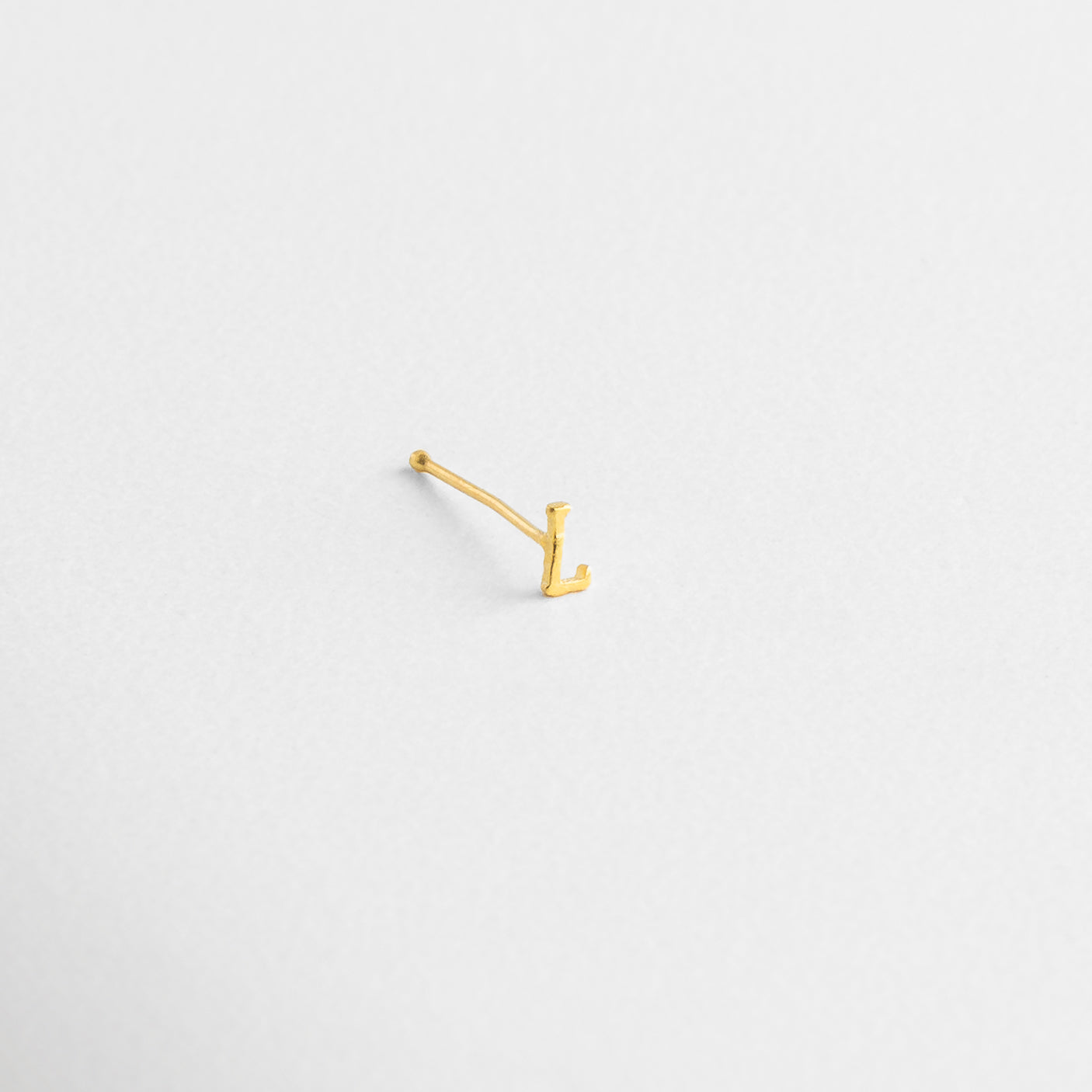 Letra dorada sobre fondo claro, Detalle de la curva o línea de la letra, Ángulo que muestra volumen del diseño, Relieve suave en Oro 18K, Perfil metálico perfectamente contorneado
