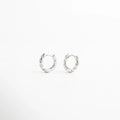 Aretes de aro plateados pequeños con diseño trenzado, estilo moderno y elegante, Arracadas plateadas con textura entrelazada, joyería minimalista y sofisticada.