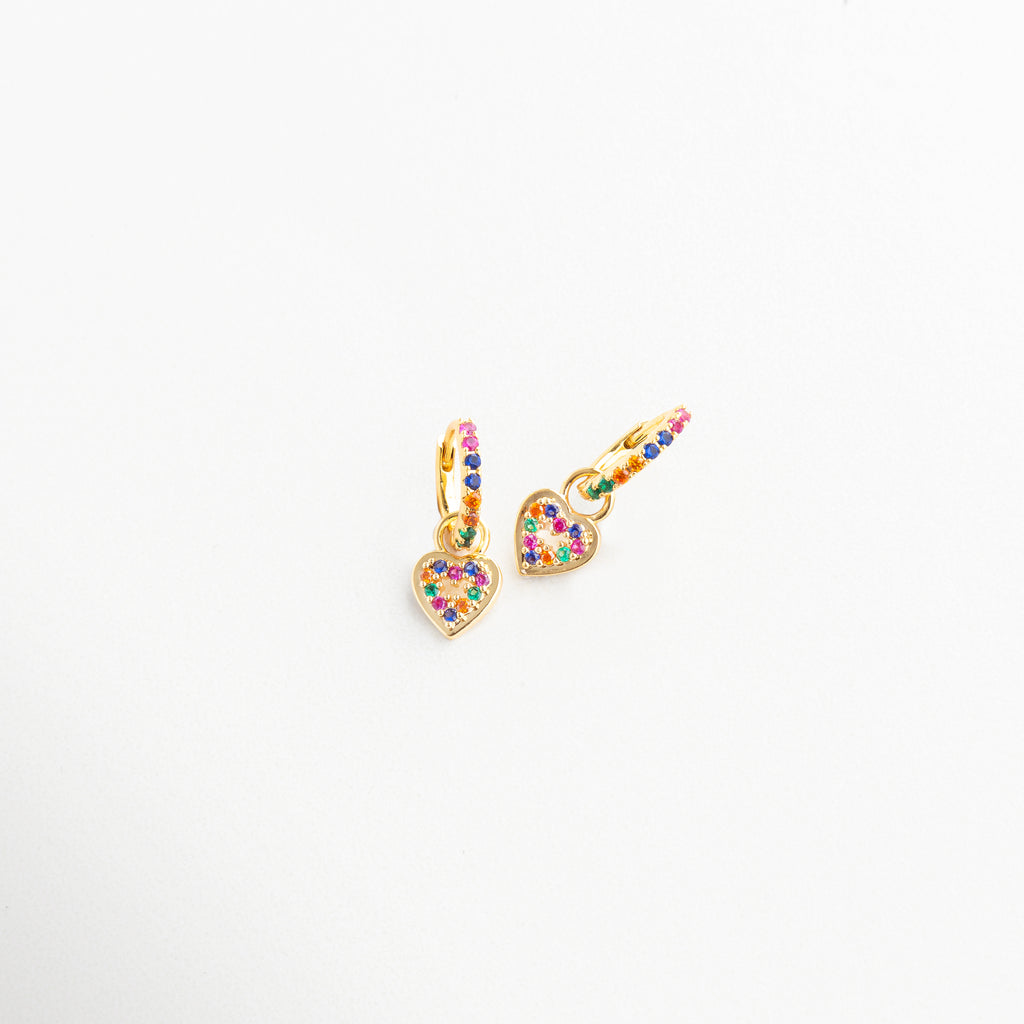 Aretes vistos de lado con corazón brillante colgante, Arracadas doradas con colgante colorido en perspectiva, Diseño curvo con charm en forma de corazón multicolor, Vista en ángulo de pendientes con toque romántico