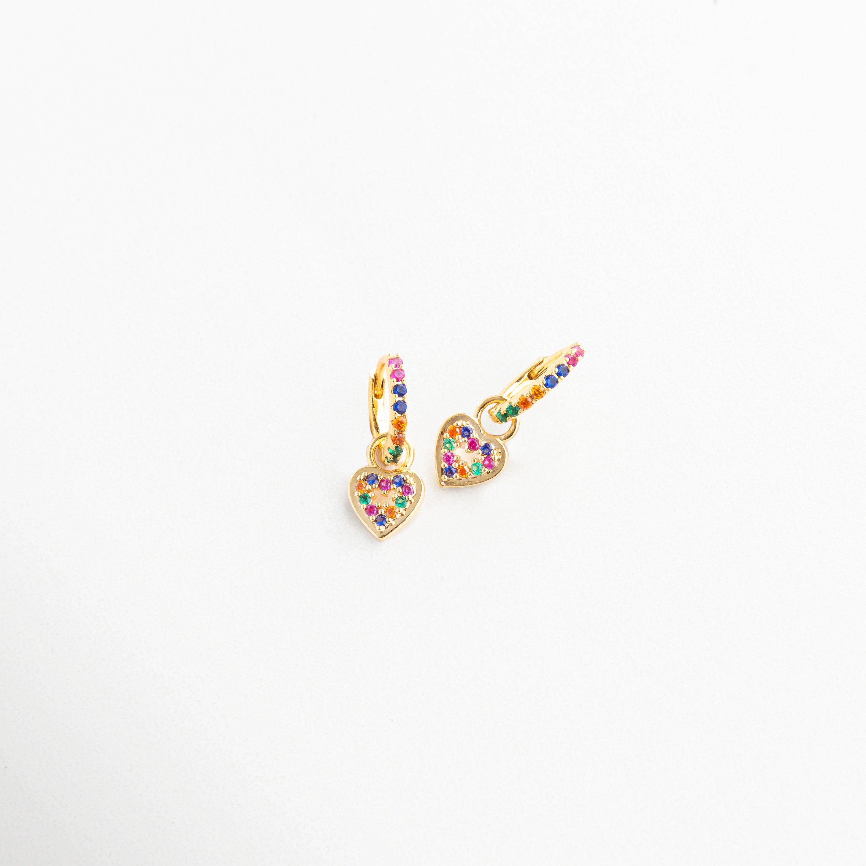 Aretes vistos de lado con corazón brillante colgante, Arracadas doradas con colgante colorido en perspectiva, Diseño curvo con charm en forma de corazón multicolor, Vista en ángulo de pendientes con toque romántico