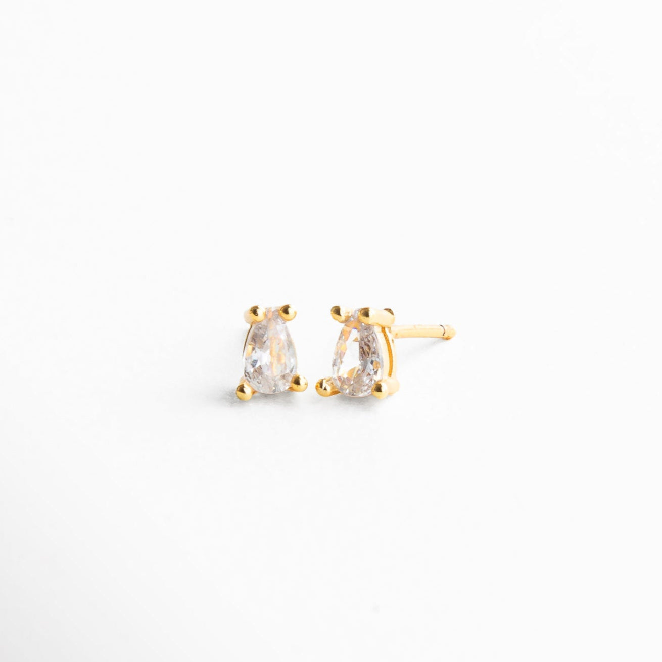 Aretes pequeños de 0.6 x 0.2 cm con piedra brillante, Proporción real de mini aretes dorados con zirconia, Studs dorados con zirconia en tamaño discretoMedida visible de arete mini con diseño clásico 