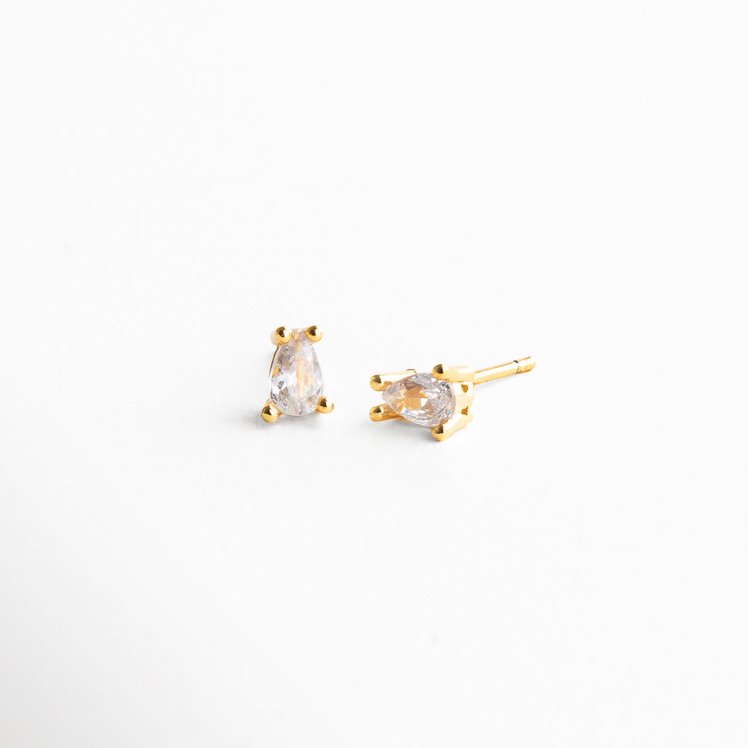 Detalle del mini stud dorado con zirconia, Primer plano del acabado pulido y piedra brillante, Textura pulida y zirconia engastada en arete dorado, Acabado en chapa de oro 14K con zirconia