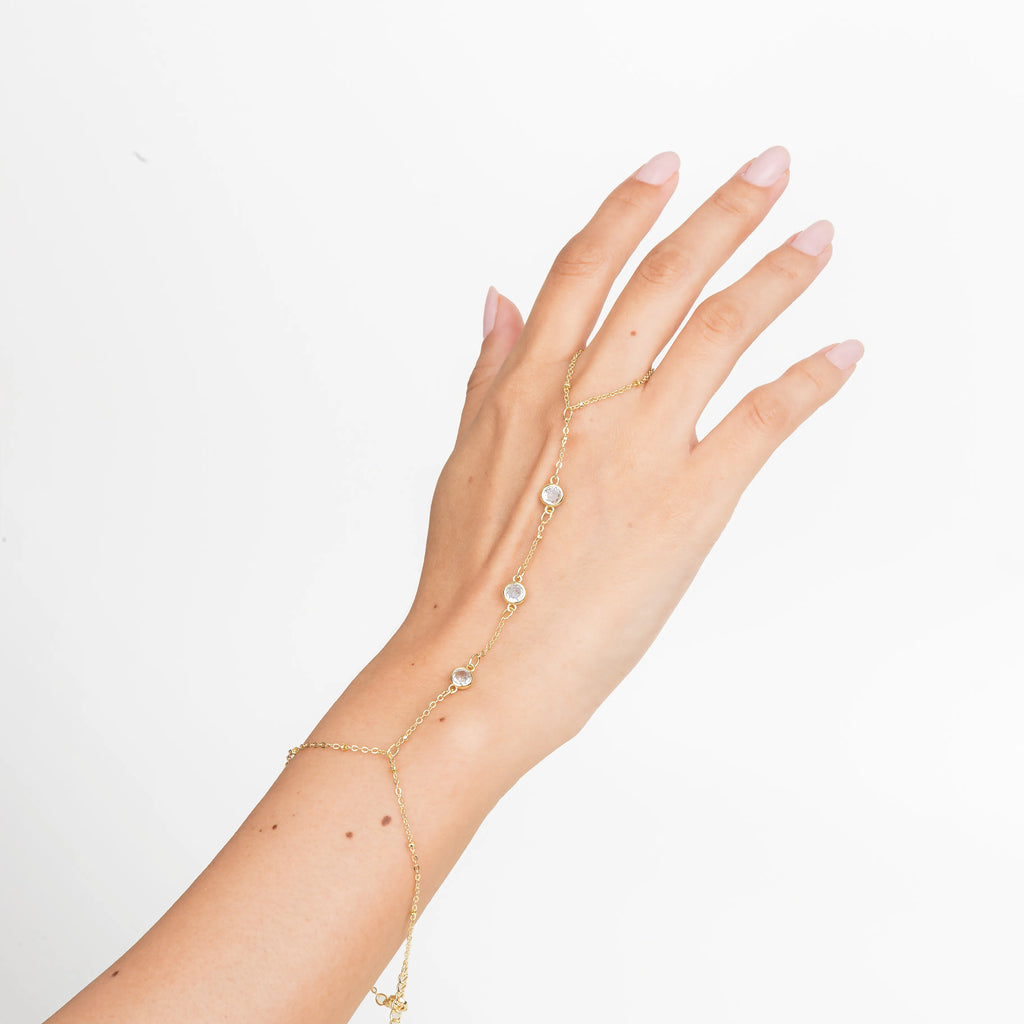 pulsera con anillo en mano, joyería femenina en uso, hand chain elegante, pulsera delicada mujer, accesorios chic, joyería minimal, pulsera dorada moderna