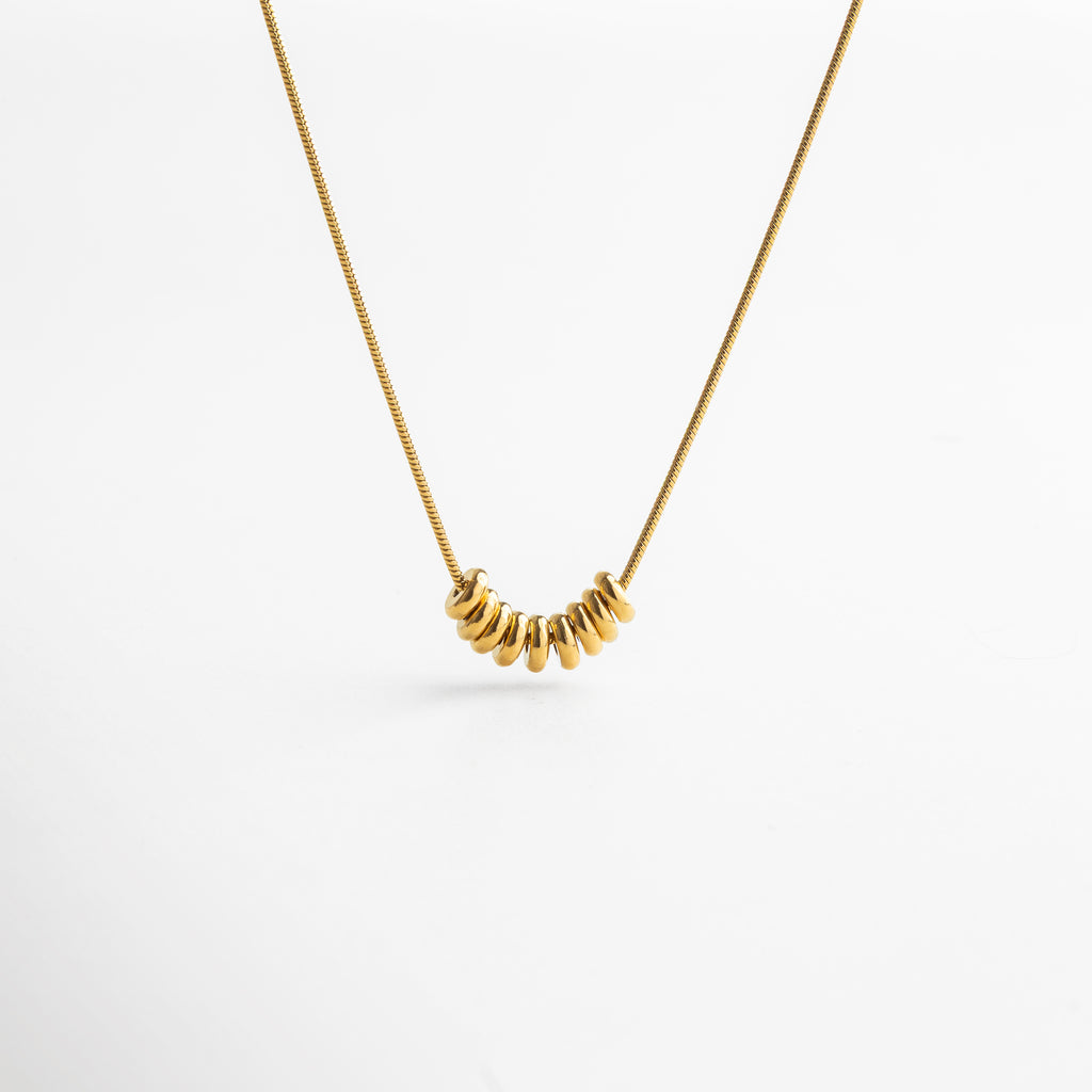 Collar Lane dorado con fina cadena en acero inoxidable 316 y recubrimiento enchapado en oro 18K, decorada con pequeños círculos pulidos que reflejan la luz y aportan movimiento al diseño