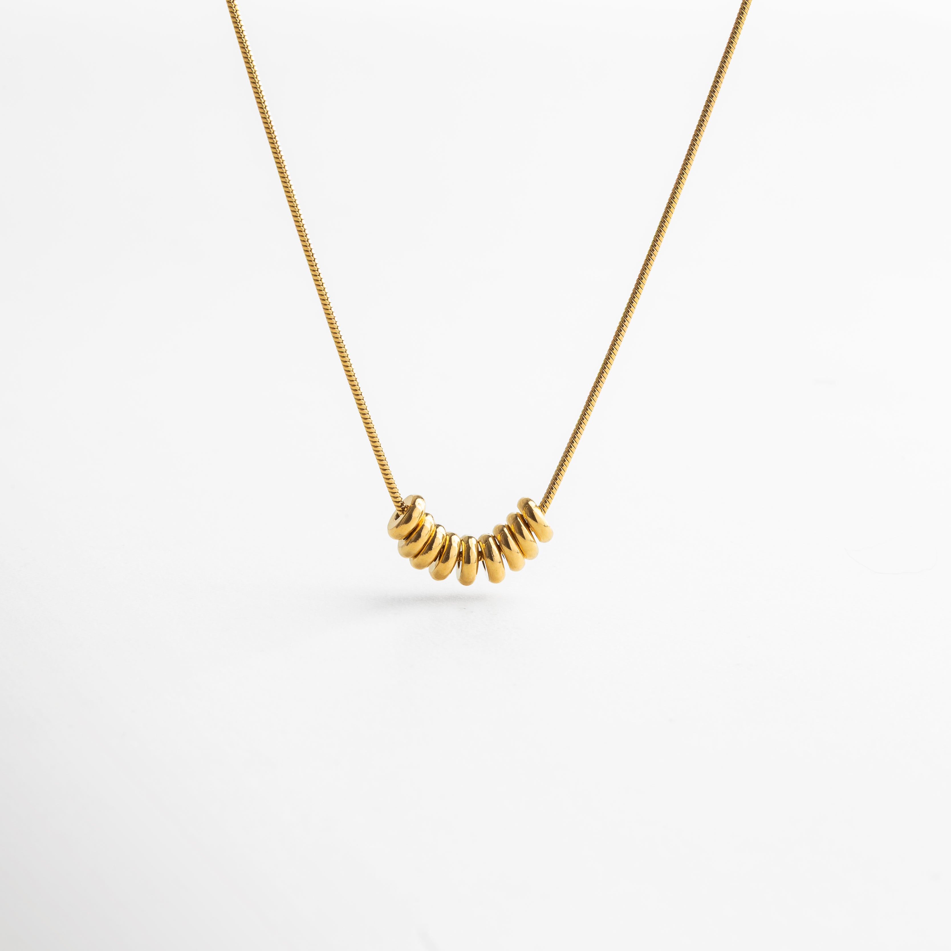 Collar Lane dorado con fina cadena en acero inoxidable 316 y recubrimiento enchapado en oro 18K, decorada con pequeños círculos pulidos que reflejan la luz y aportan movimiento al diseño