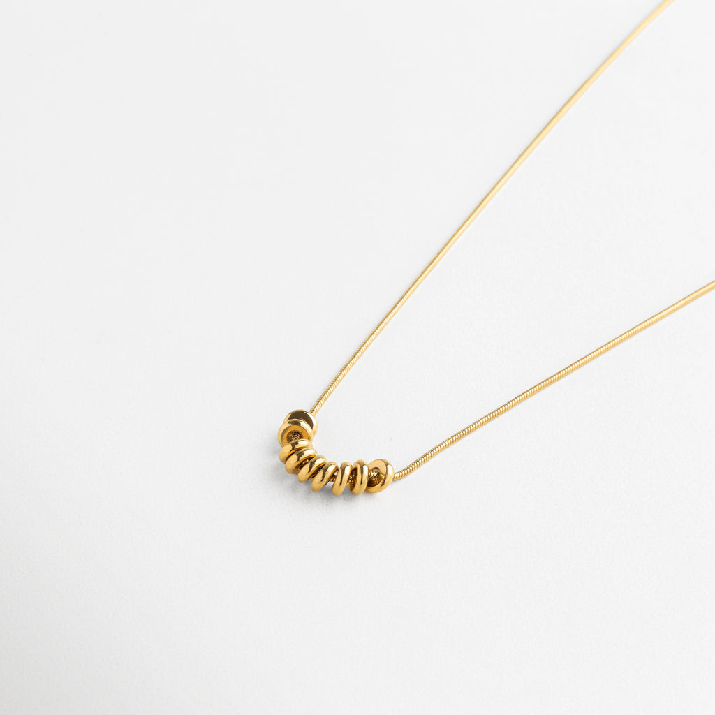 Acercamiento a la textura lisa y pulida de cada círculo dorado, mostrando el sutil reflejo metálico y la calidad del chapado en oro 18K sobre acero inoxidable