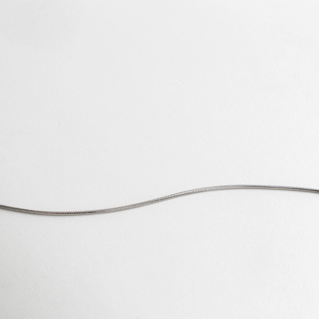 Primer plano de cadena y dije minimalista con acabado plata, pequeños detalles circulares que aportan textura y sofisticación, pieza ideal para combinar con otras joyas o usar sola con elegancia discreta