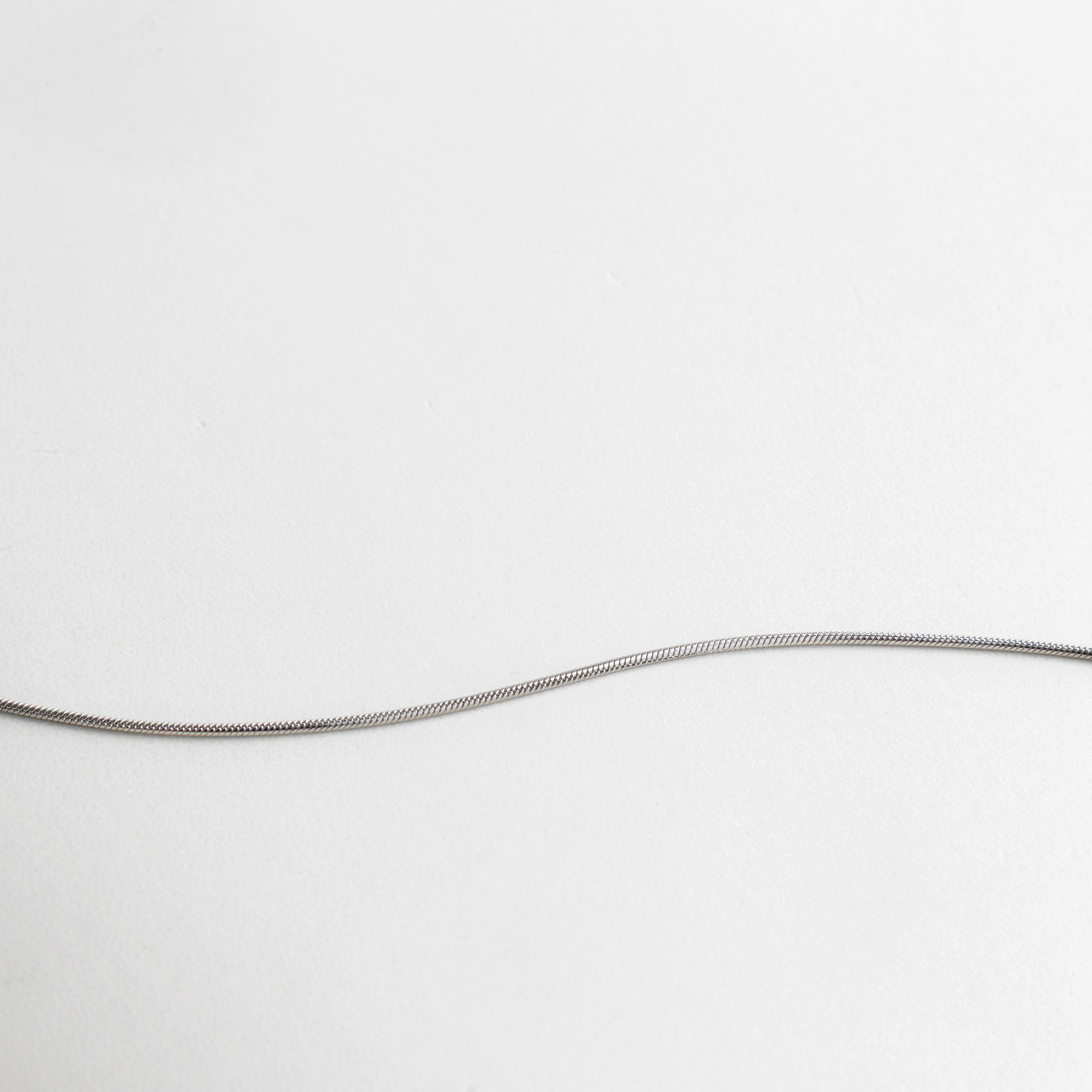 Primer plano de cadena y dije minimalista con acabado plata, pequeños detalles circulares que aportan textura y sofisticación, pieza ideal para combinar con otras joyas o usar sola con elegancia discreta