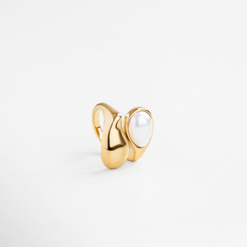 Detalle de la perla blanca en anillo dorado, Textura pulida del anillo Akari con perla central, Incrustación de perla en diseño dorado fluido, Acabado brillante y curvo con perla como protagonista