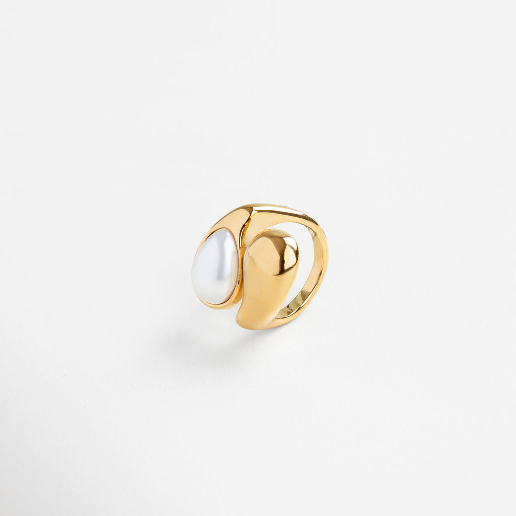Anillo con perla en estructura orgánica desde perfil, Curvas modernas del anillo Akari con perla vista lateral, Diseño fluido en dorado con perla elevada, Anillo escultórico dorado con perla desde un ángulo