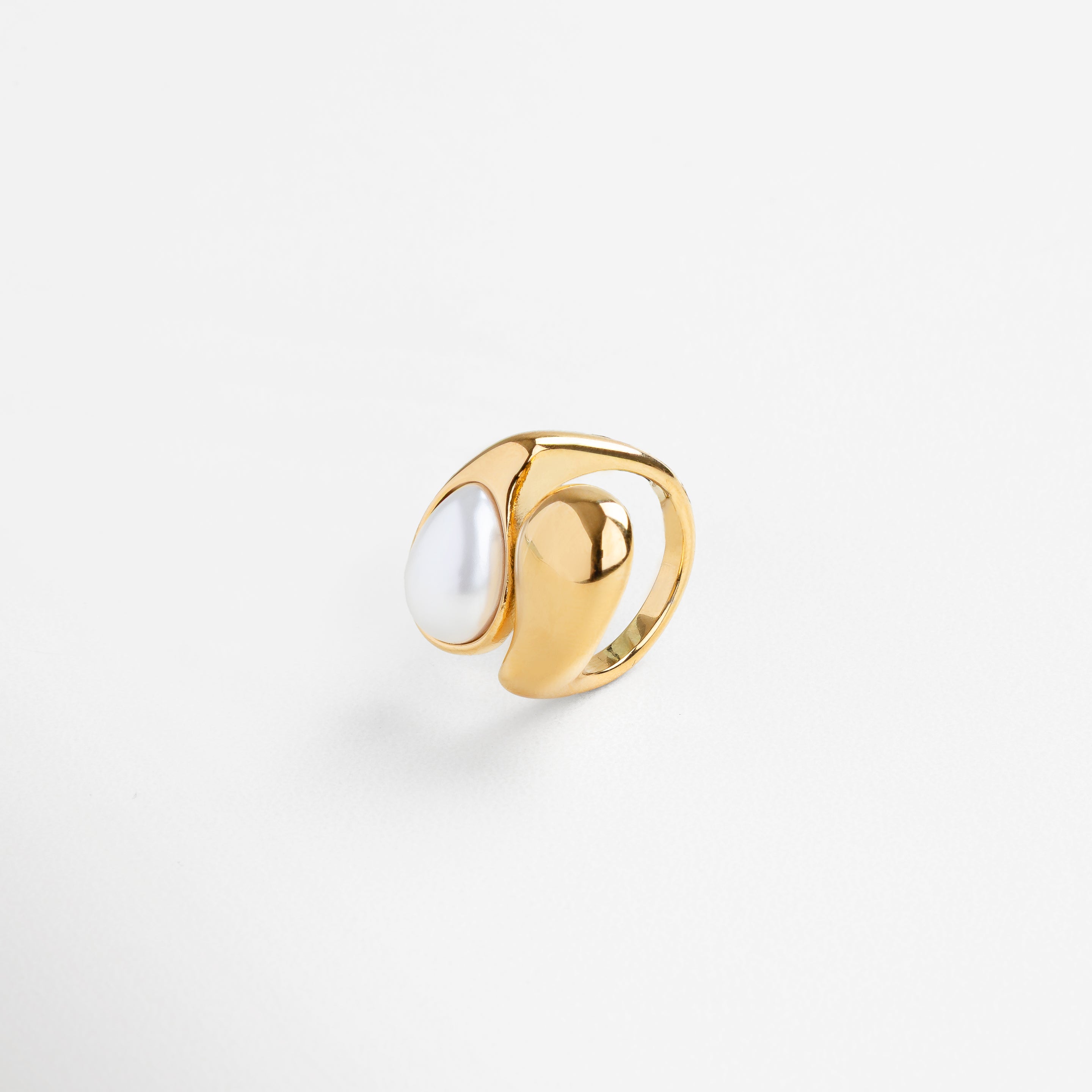 Anillo con perla en estructura orgánica desde perfil, Curvas modernas del anillo Akari con perla vista lateral, Diseño fluido en dorado con perla elevada, Anillo escultórico dorado con perla desde un ángulo