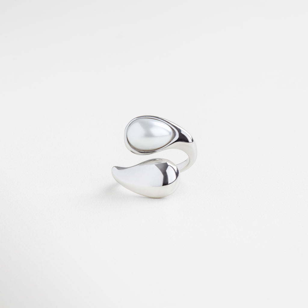 Anillo plateado con perla blanca en diseño orgánico, Joya escultural plateada con perla natural al centro, Anillo moderno en tono plateado con perla luminosa, Diseño fluido y contemporáneo con perla blanca