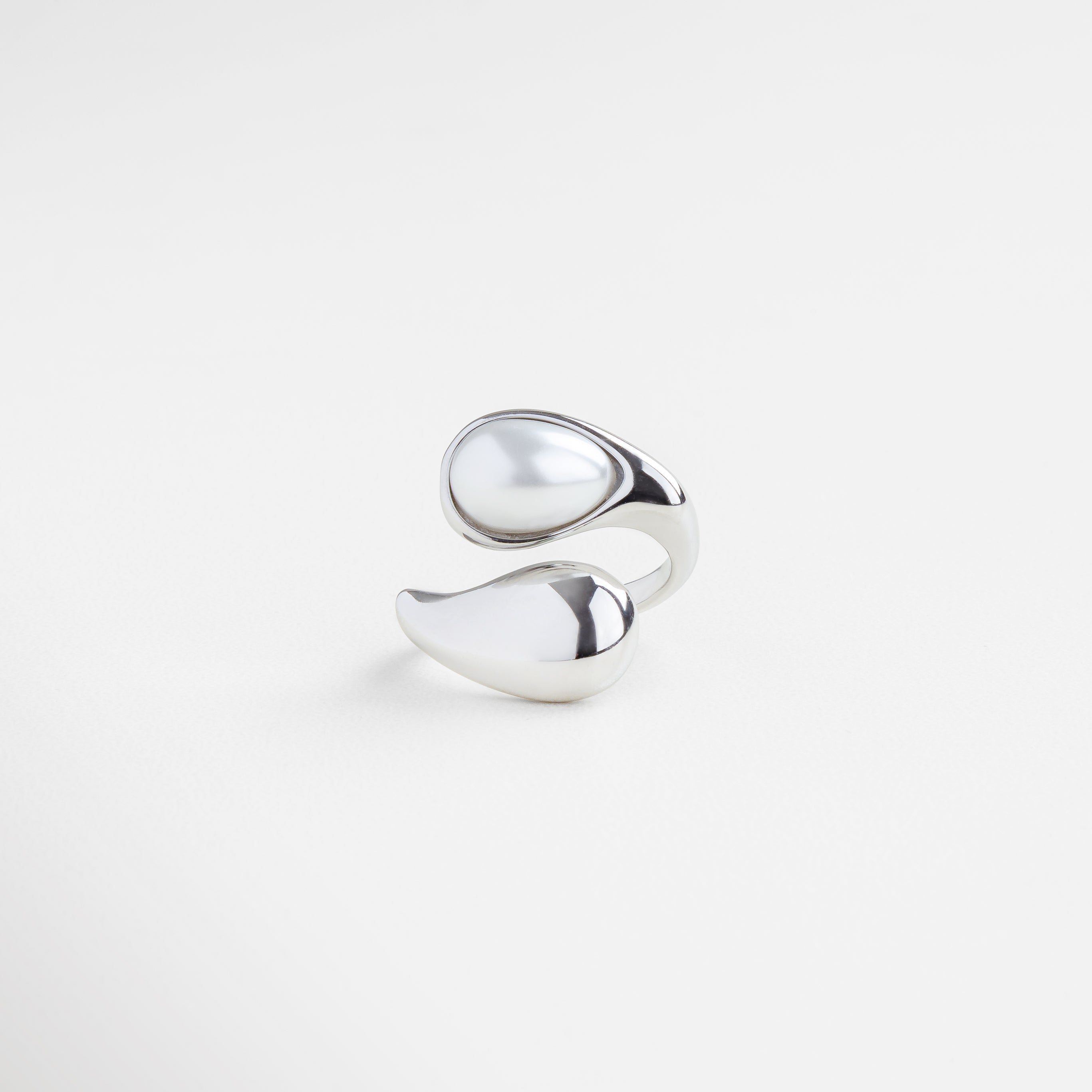 Anillo plateado con perla blanca en diseño orgánico, Joya escultural plateada con perla natural al centro, Anillo moderno en tono plateado con perla luminosa, Diseño fluido y contemporáneo con perla blanca