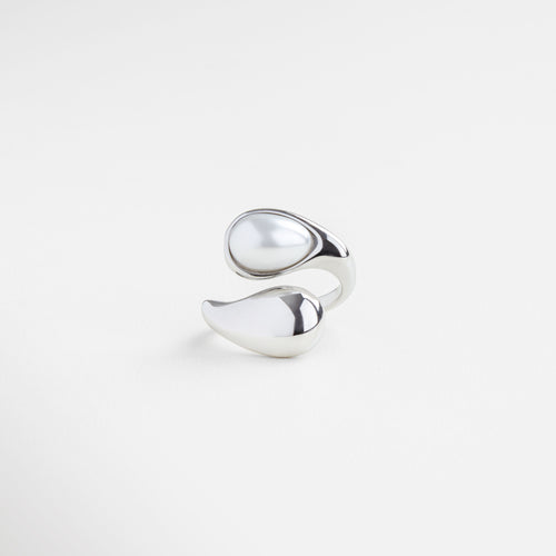 Anillo plateado con perla blanca en diseño orgánico, Joya escultural plateada con perla natural al centro, Anillo moderno en tono plateado con perla luminosa, Diseño fluido y contemporáneo con perla blanca