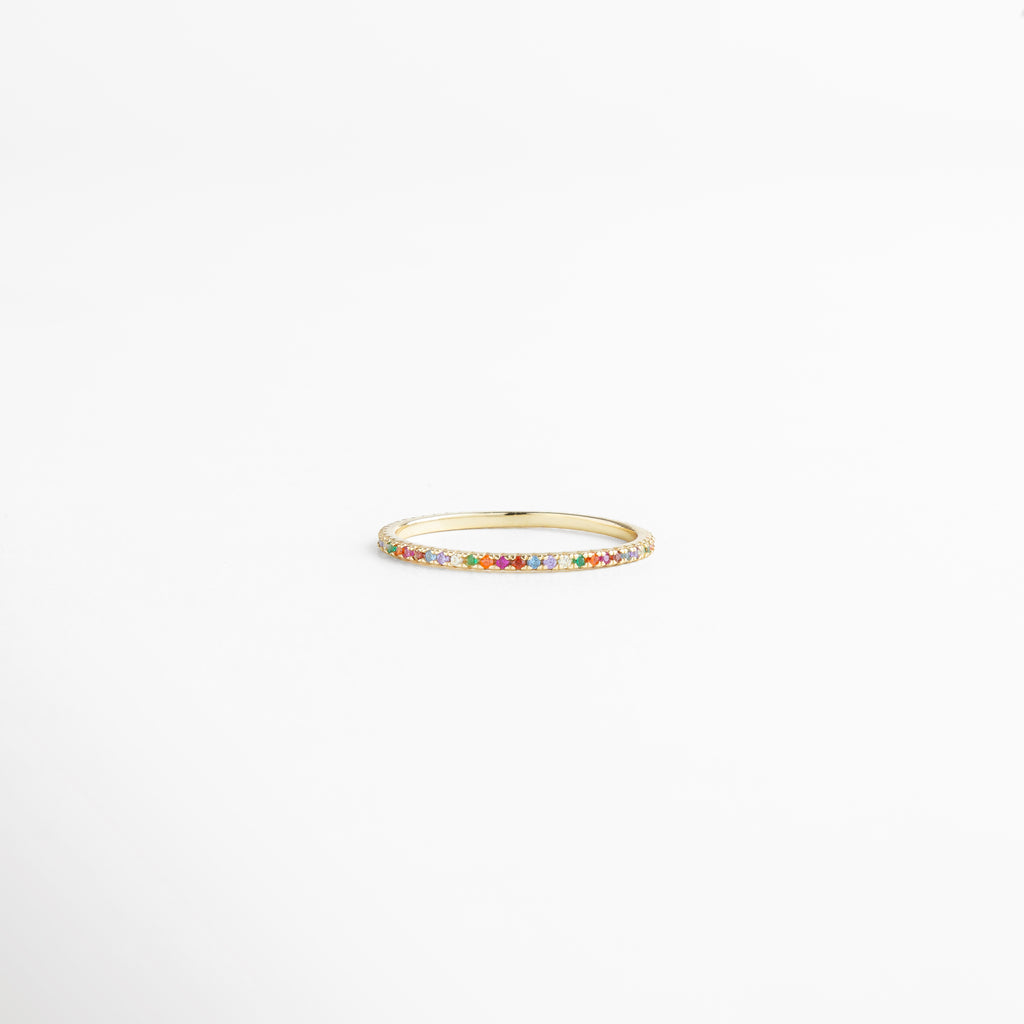 Anillo de plata Ley 925 con recubrimiento enchapado en oro 18K, incrustaciones de zirconias multicolor en diseño delicado y elegante, pieza fina de joyería minimalista mostrada en vista horizontal sobre fondo blanco.