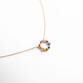 Collar dorado con dije circular adornado con piedras multicolor, diseño delicado y moderno que resalta por su brillo y color.