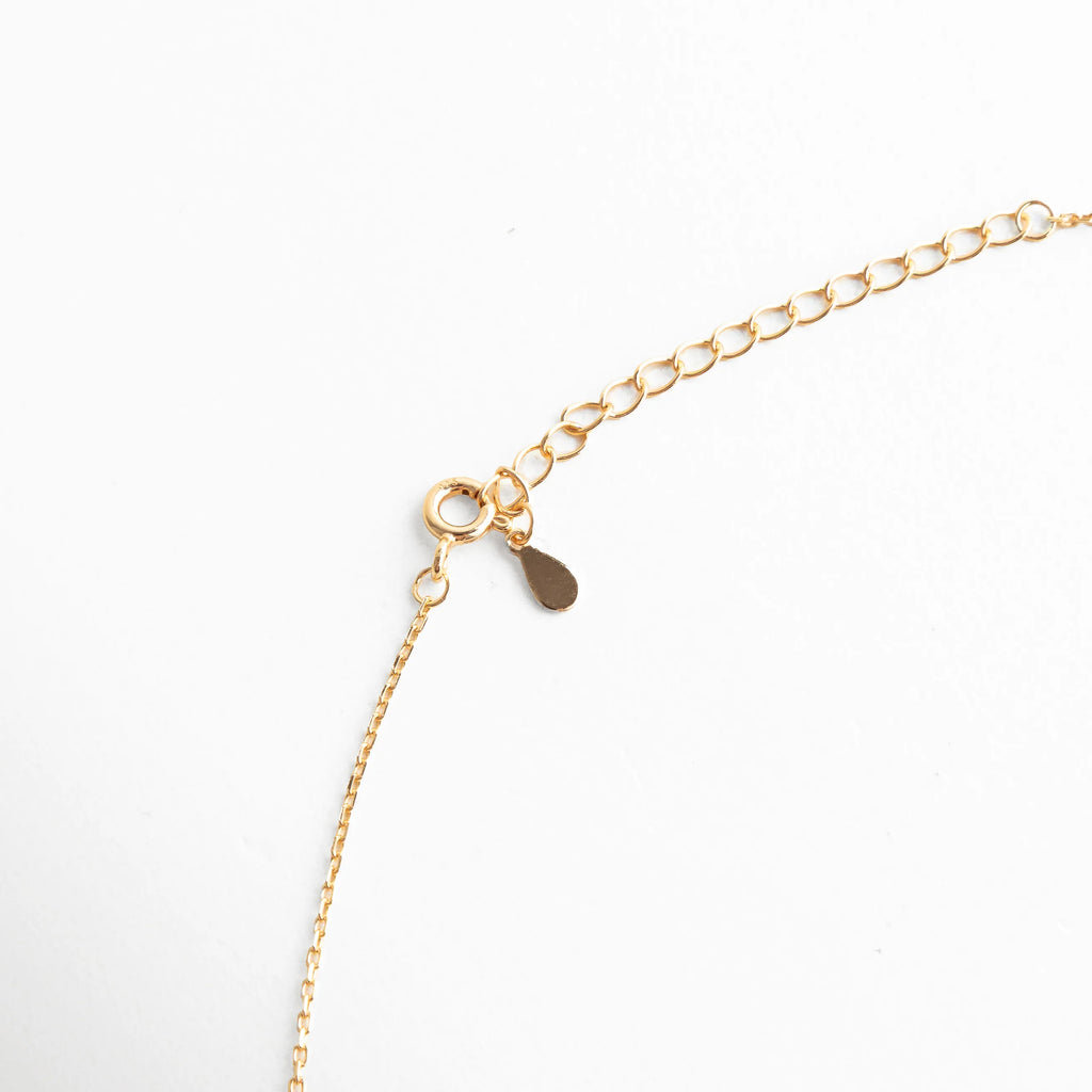 Cierre ajustable con cadena dorada y detalle de gota metálica, acabado fino que permite adaptar el largo del collar.