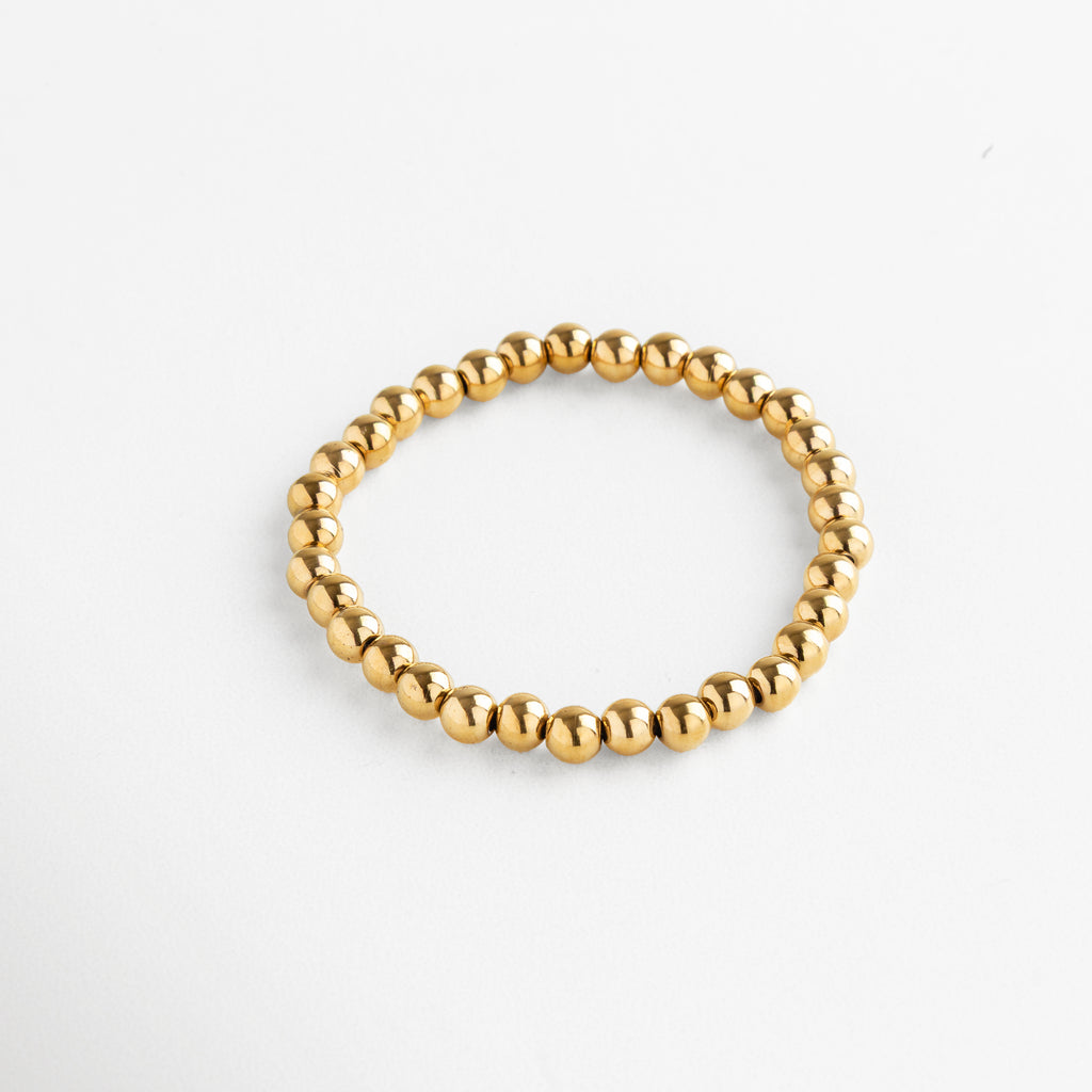 Detalle de pulsera dorada de cuentas grandes con acabado brillante, Pulsera dorada moderna con esferas metálicas grandes y pulidas.